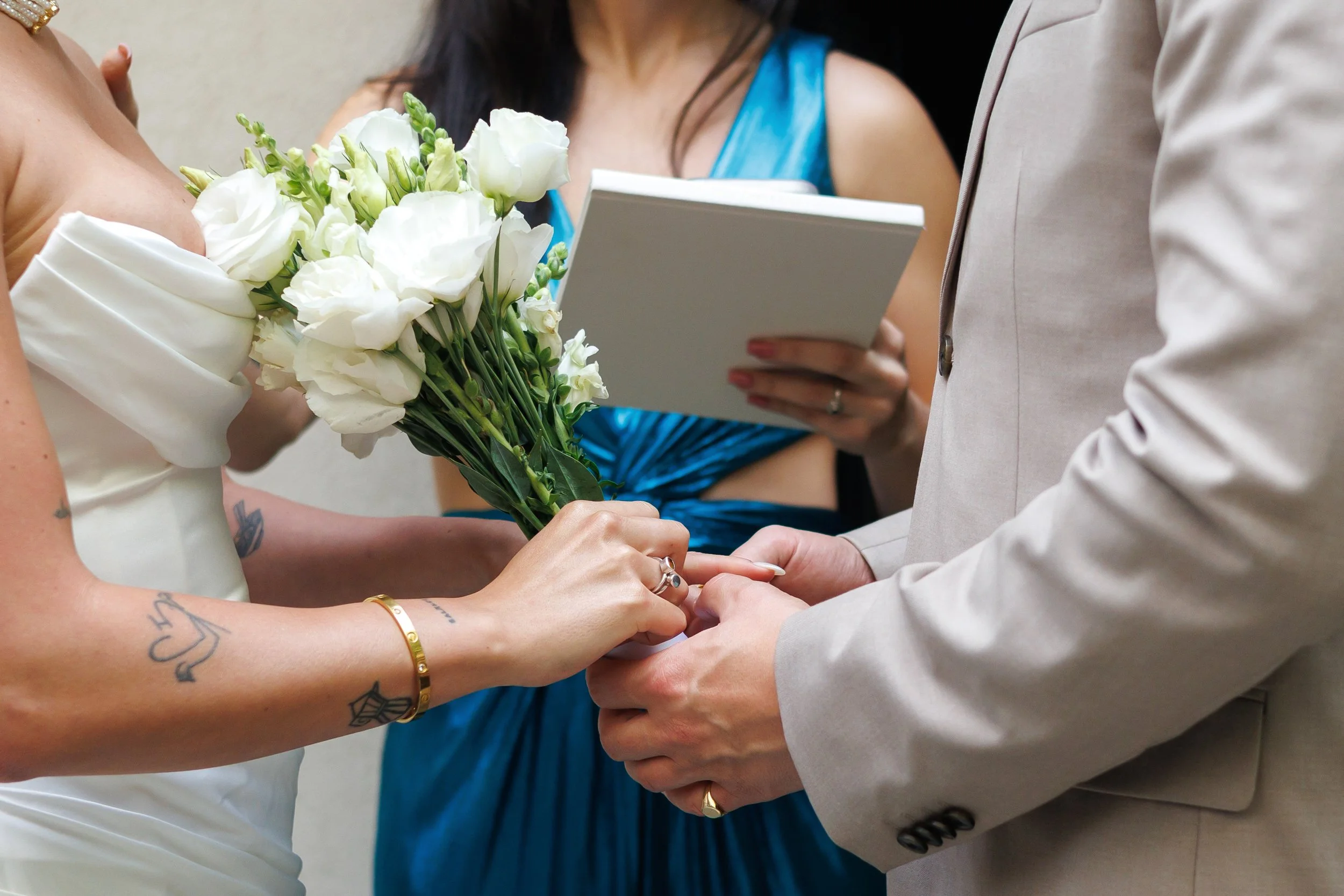 A couple walking hand in hand on a sidewalk, surrounded by columns, with the woman in a white dress and the man in a patterned shirt.
