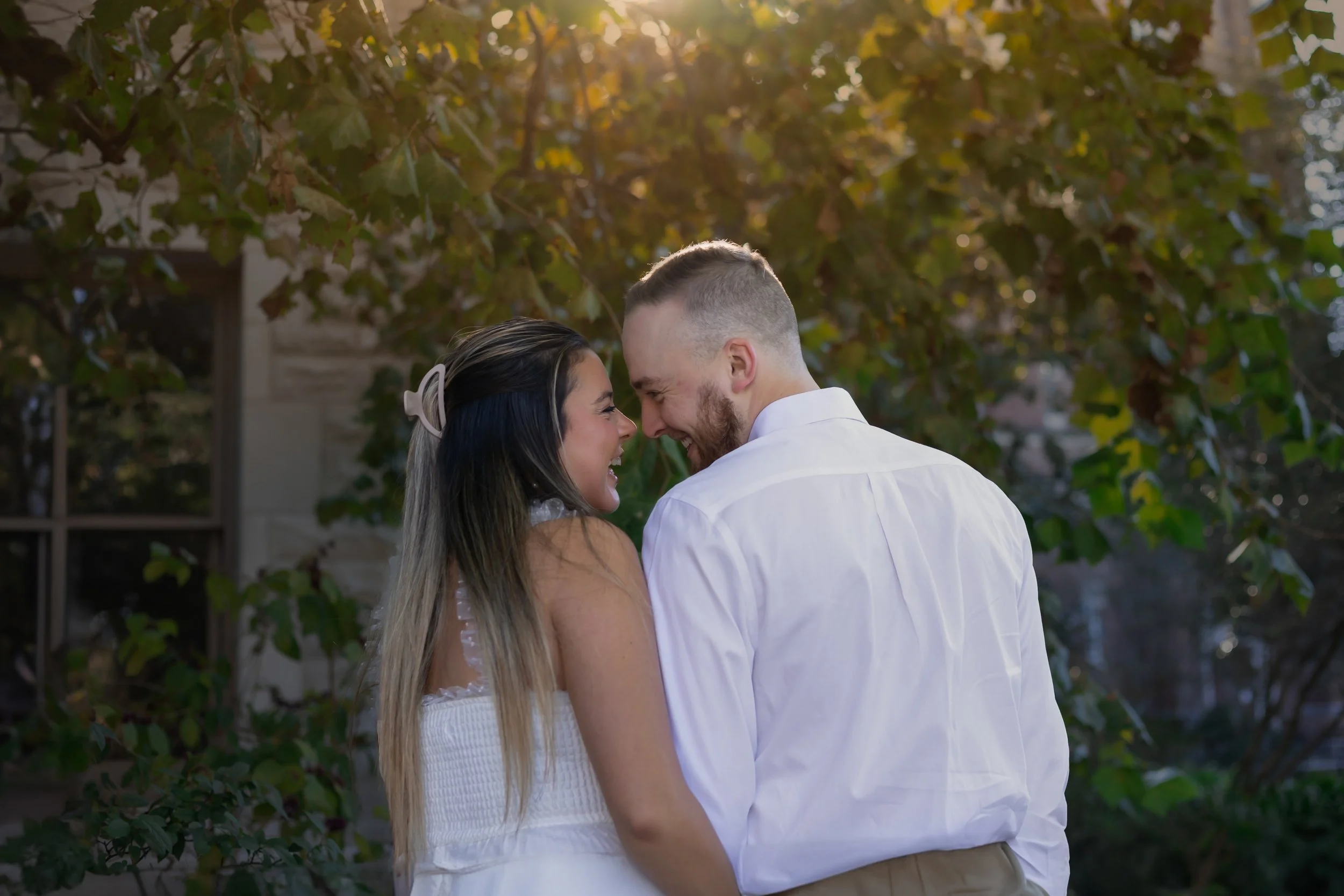Couple laughing together during engagement session in natural light, relaxed and candid moment