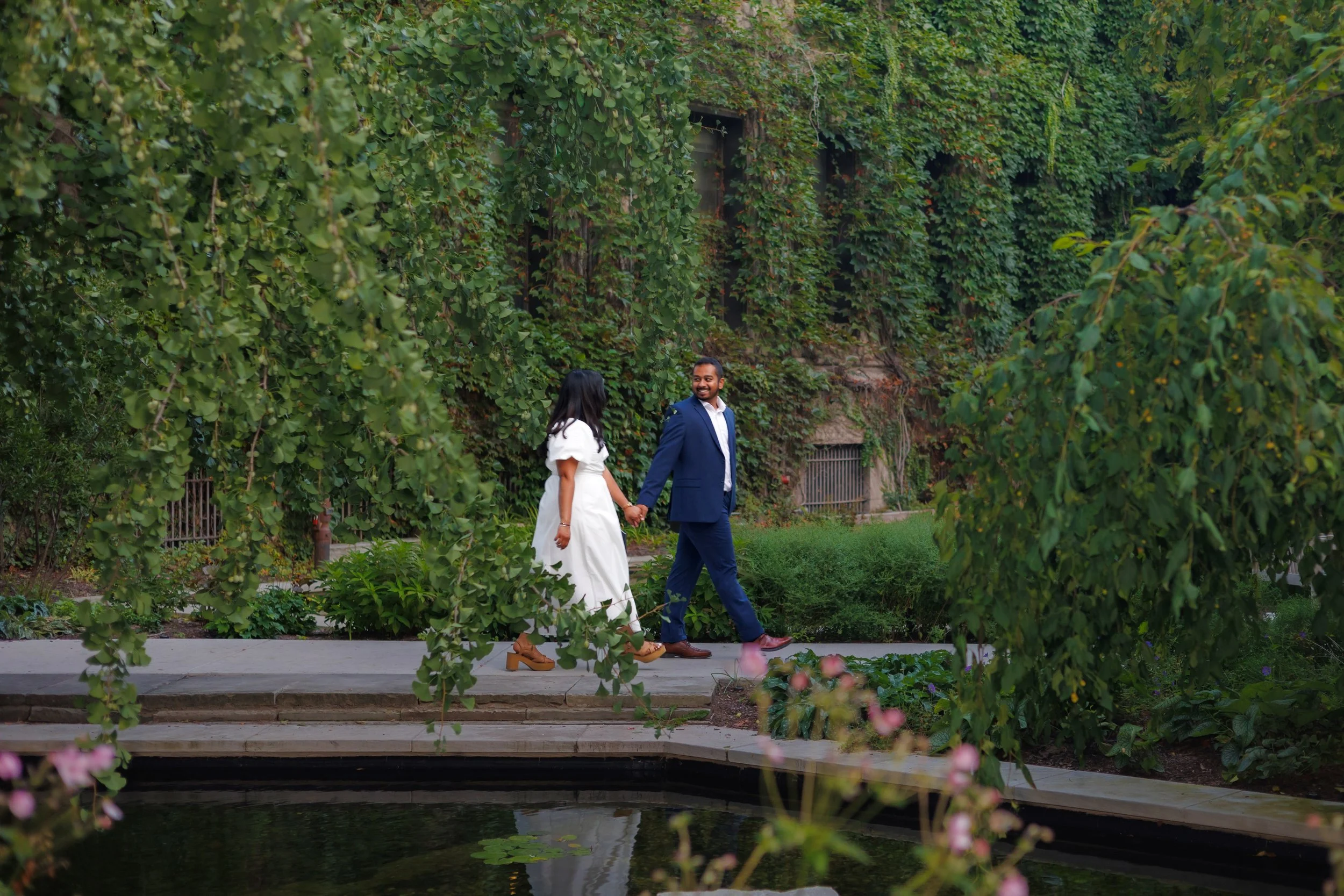 Chicago Photographer captures couple walking hand in hand though a lush romantic garden.