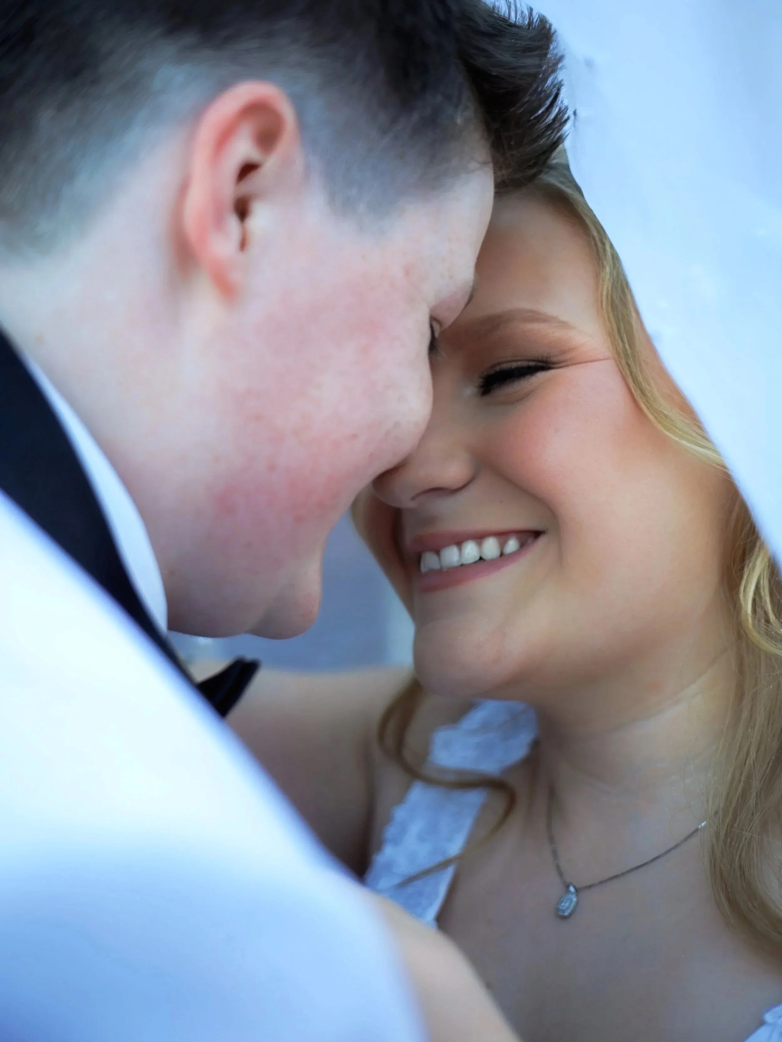 Chicago wedding photographer capturing a bride and groom under a veil in soft color tones, close-up romantic and intimate wedding portrait