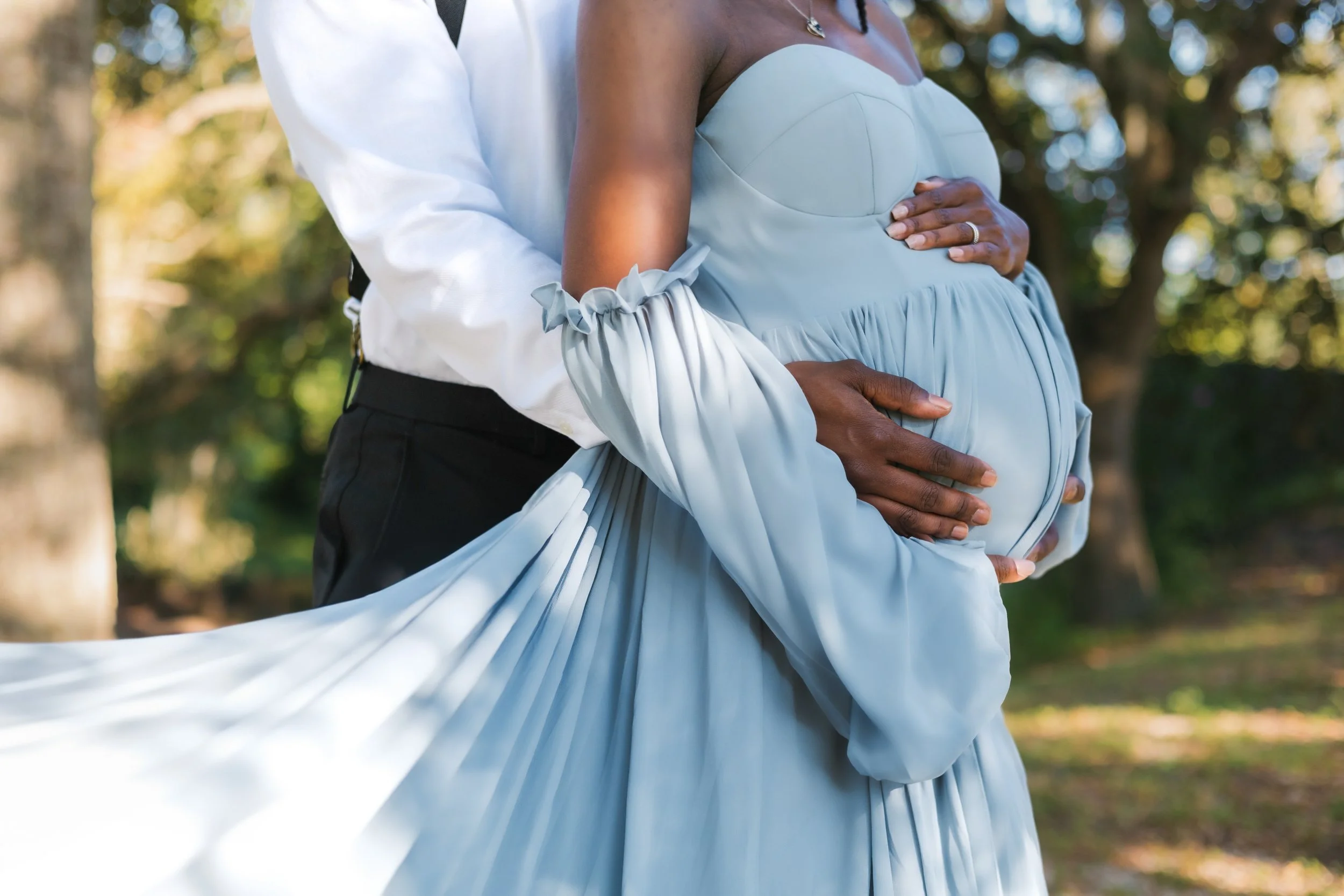 Chicago maternity photographer capturing an intimate close-up of hands resting on a baby bump, soft light and emotional connection