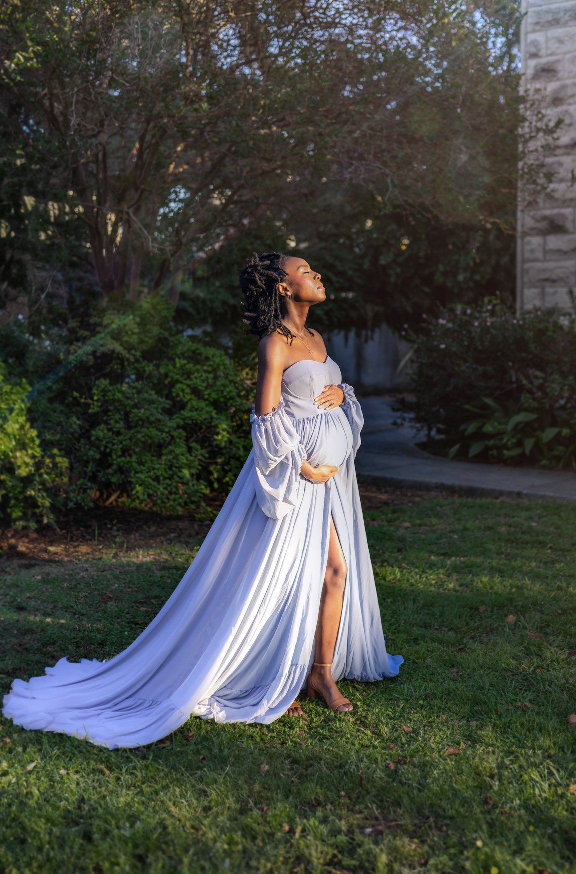 Chicago maternity photographer capturing a pregnant woman folding baby clothes into a basket outdoors near a fountain, candid and meaningful maternity moment celebrating preparation and anticipation