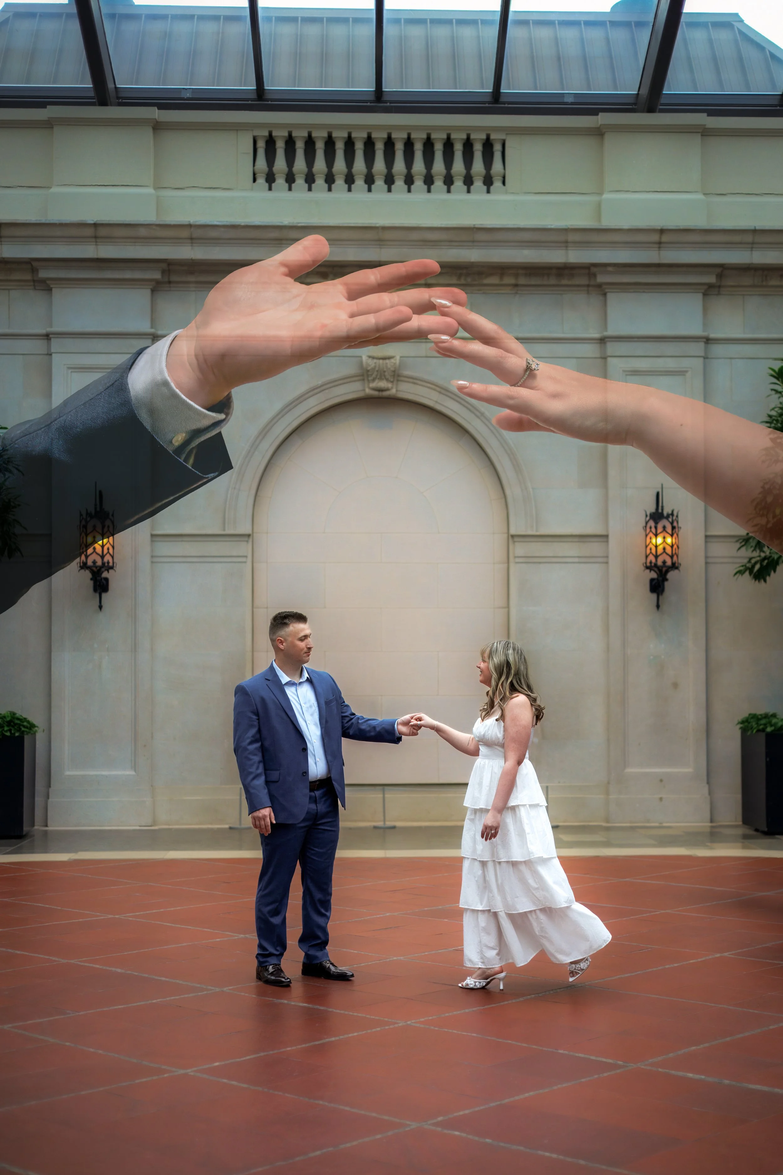Double exposure portrait of a couple dancing inside the Columbus Museum of Art, with translucent overlapping hands reaching toward each other above them.
