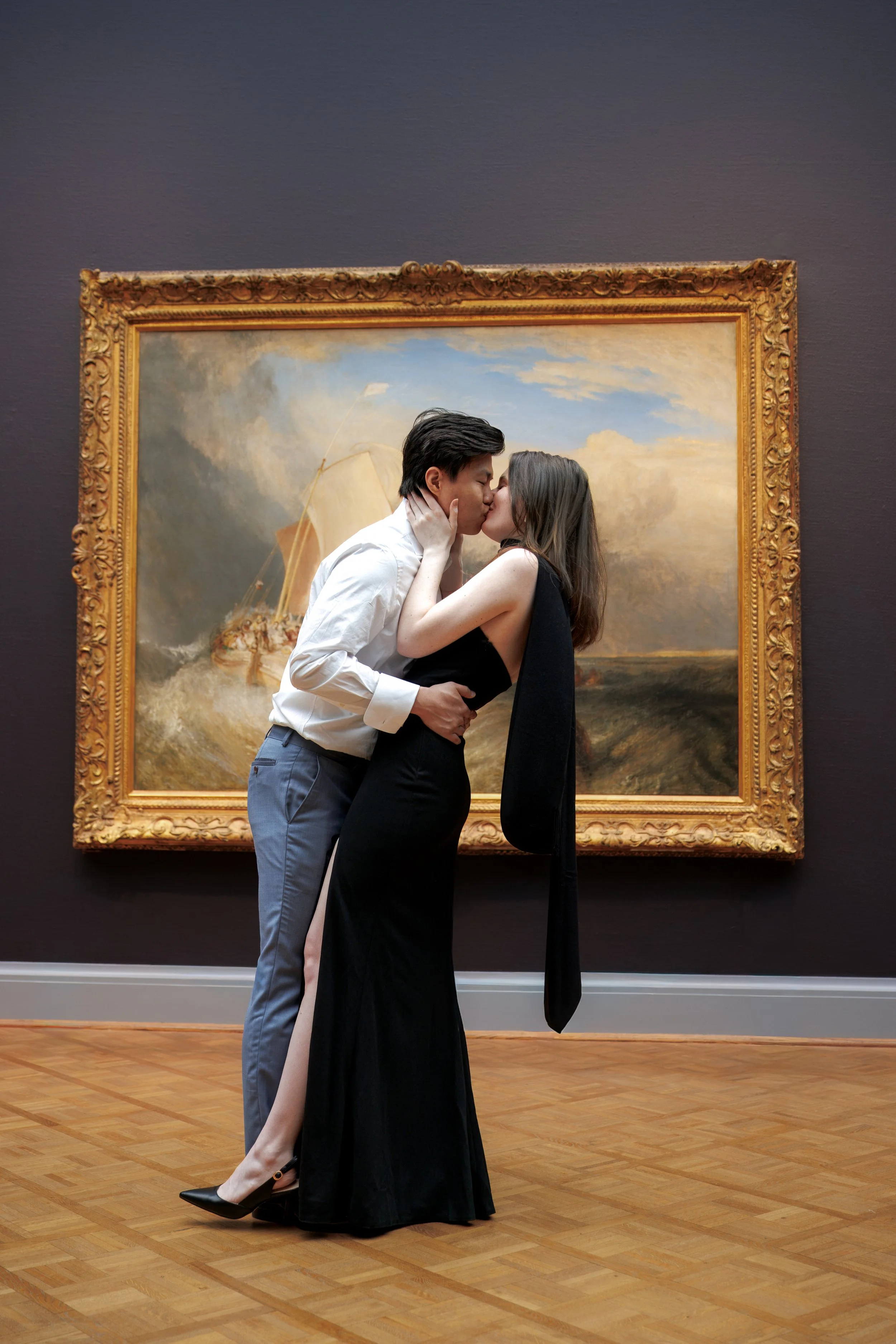 Couple kissing in front of a framed painting inside the Art Institute of Chicago, blending romance with timeless gallery elegance.