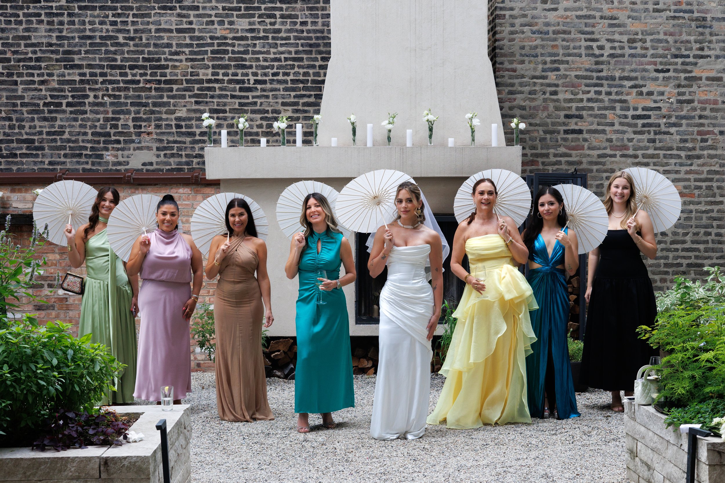 Bridal party holding white parasols and smiling together during a wedding celebration in Chicago courtyard