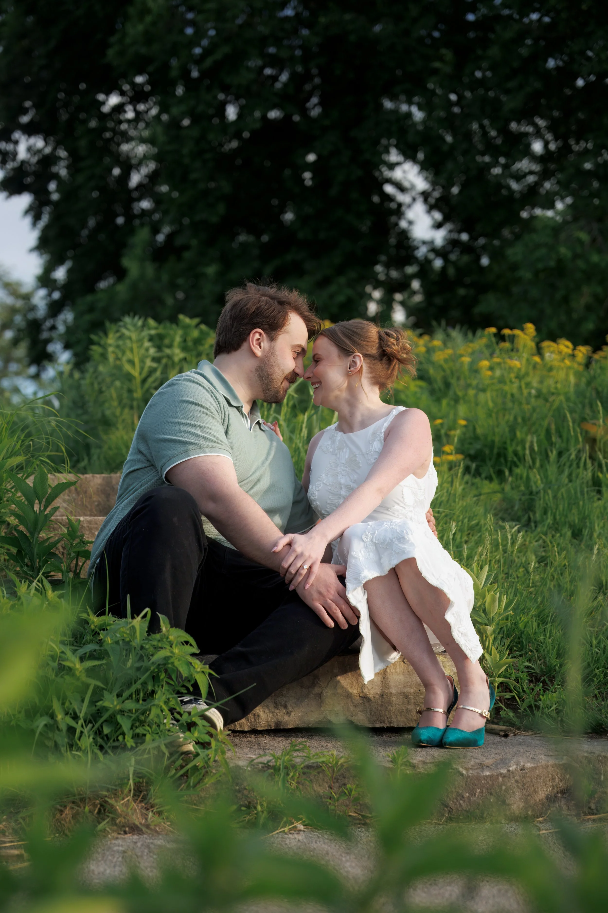 a couple sitting on stone steps in a field of wildflowers.