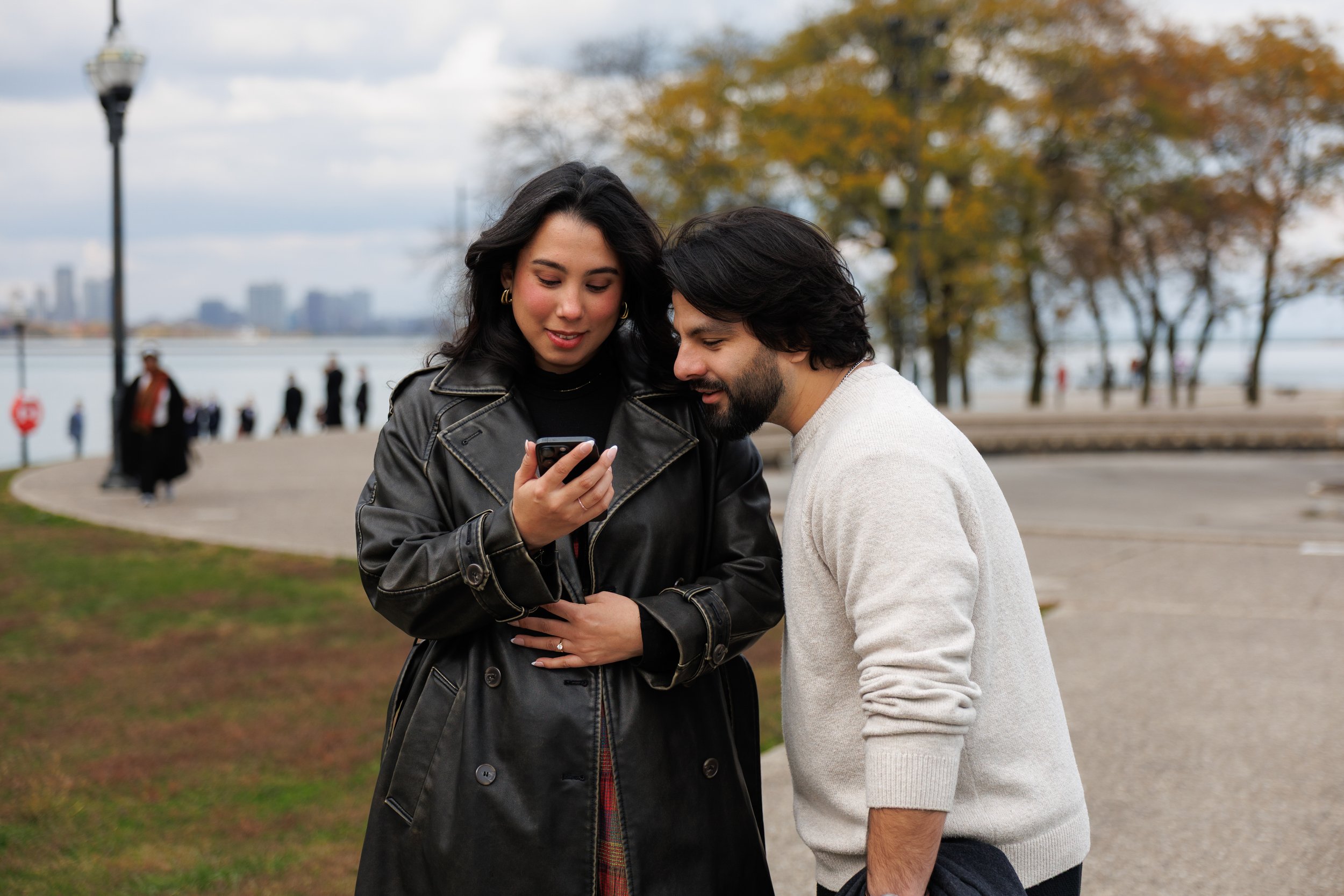 Couple looking at their wedding photos together on a phone, smiling and reacting during a candid outdoor moment