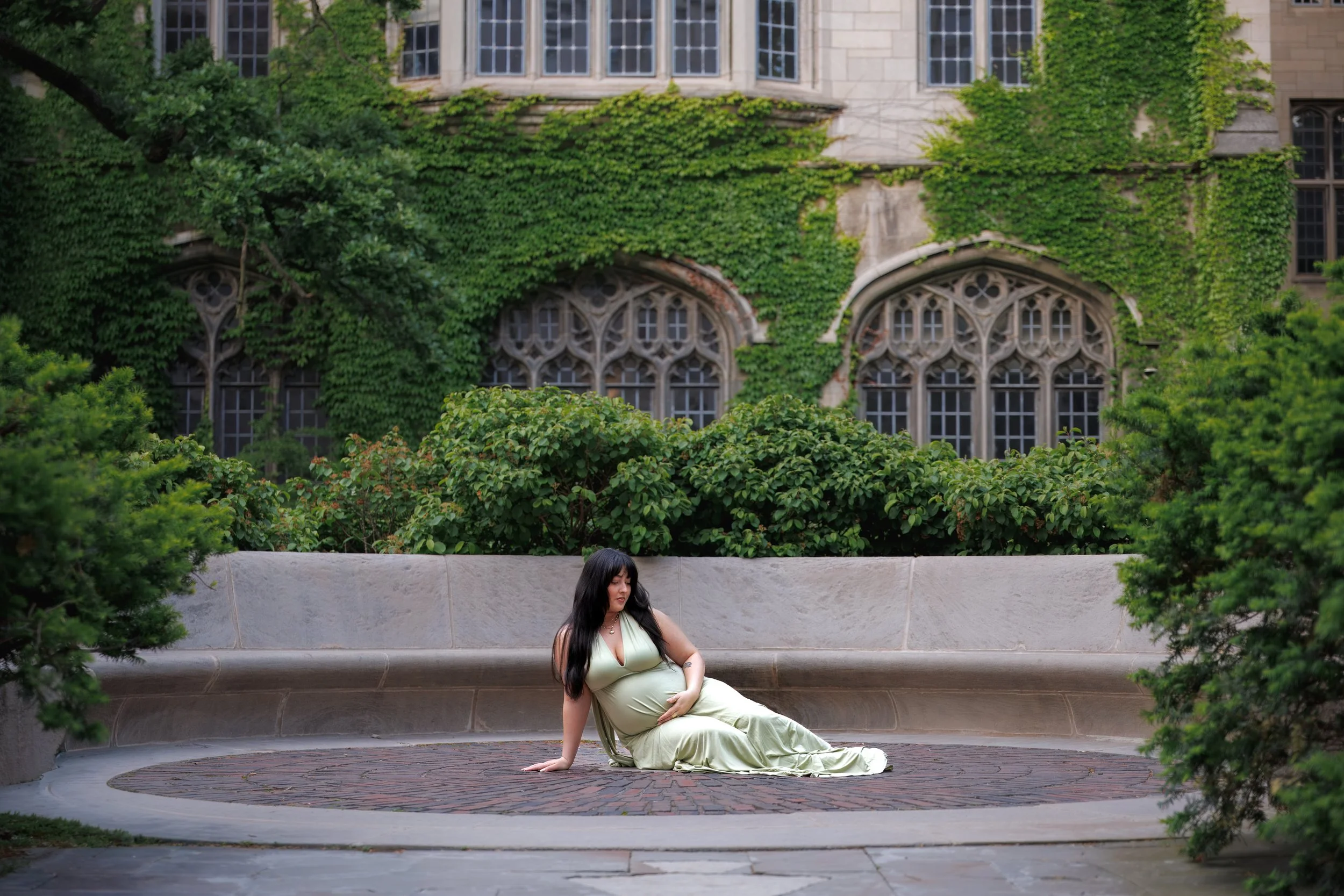 Chicago maternity photographer capturing a pregnant women with her hand on her bump sitting in front of an ivy covered building