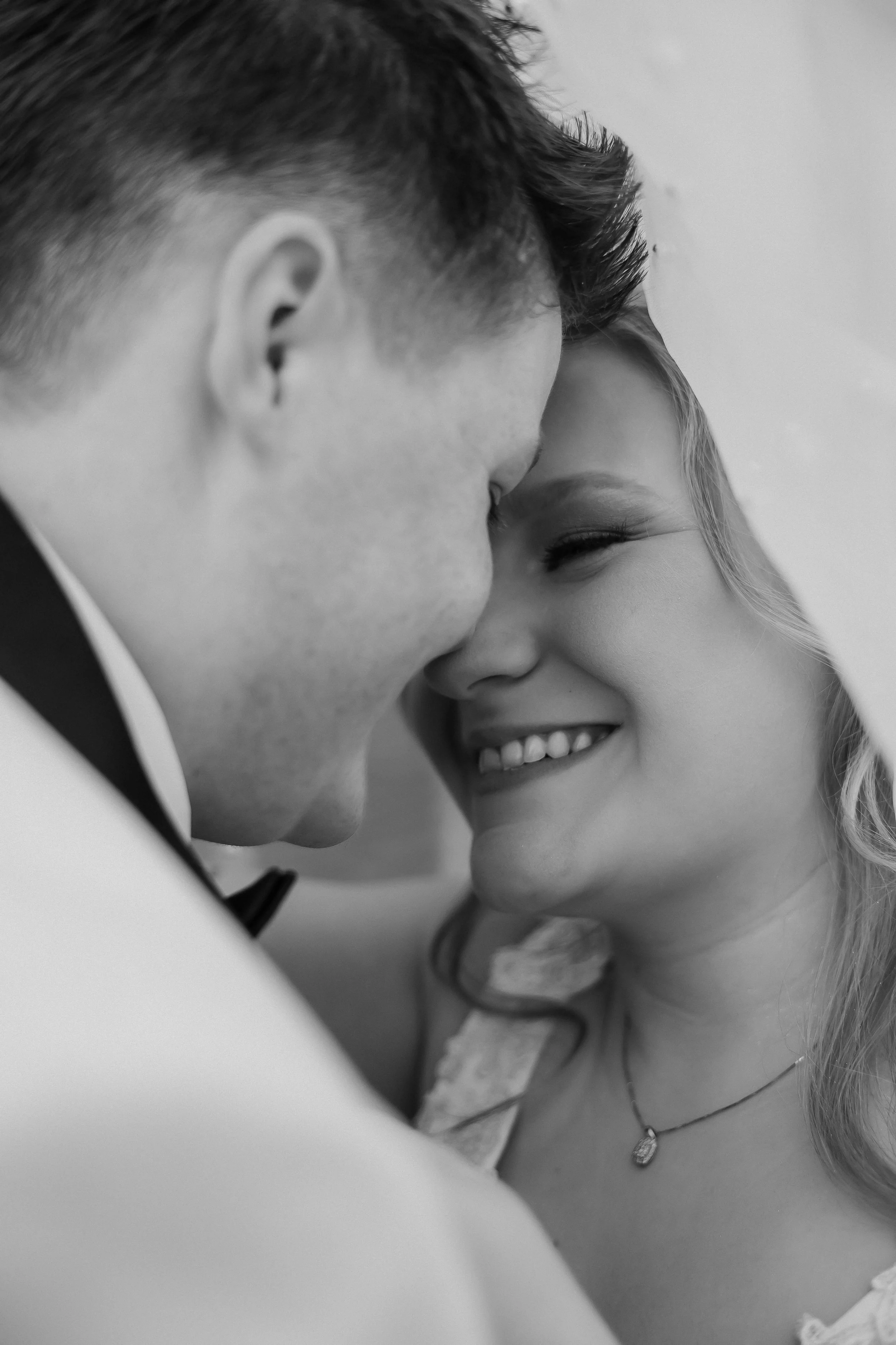 A black-and-white photo of a couple close together, smiling and touching foreheads, during a special moment. Chicago wedding photographer