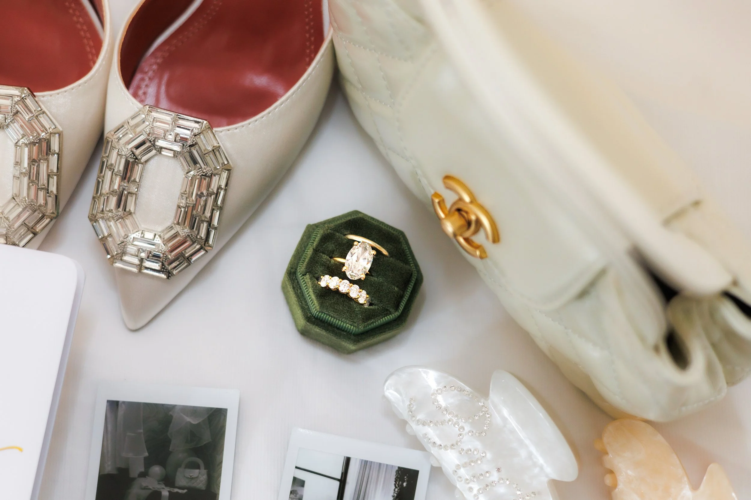 Chicago wedding photographer captures a lay flat of rings, shoes, a bag, hair clips, and polaroids 