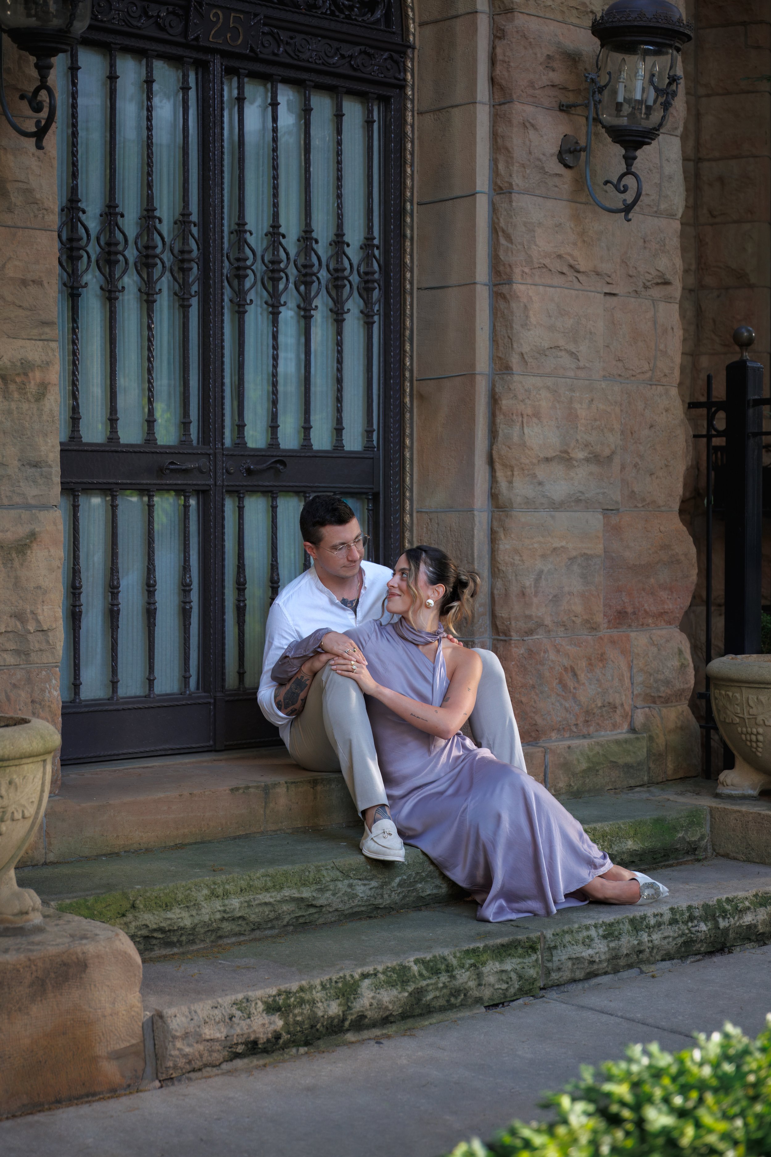 Engaged couple sitting together on stone steps outside a historic Chicago building, sharing a quiet moment during their engagement session.