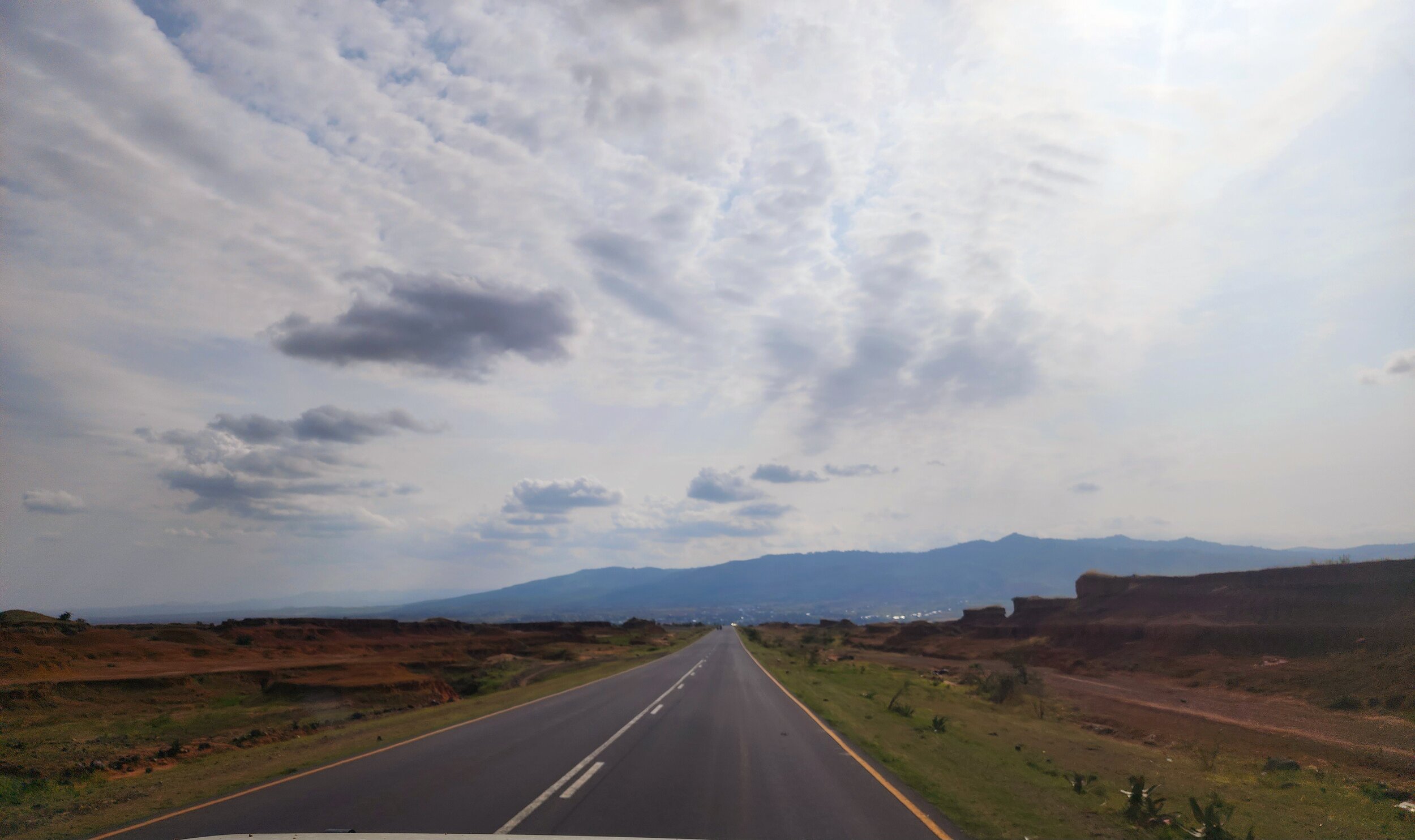 Open road with cloudy sky and mountains in the distance in Ethiopia.