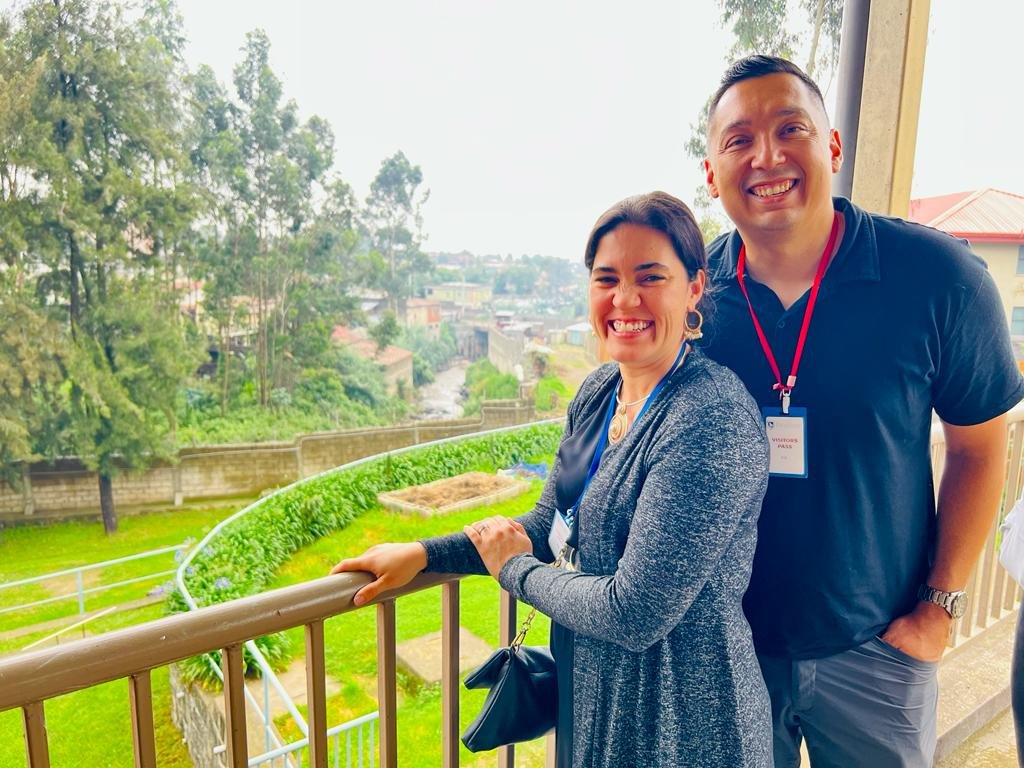 Luis Cobos, PE and Dr. Rachel Cobos smiling on a balcony in Ethiopia with a scenic view of greenery and trees in the background.