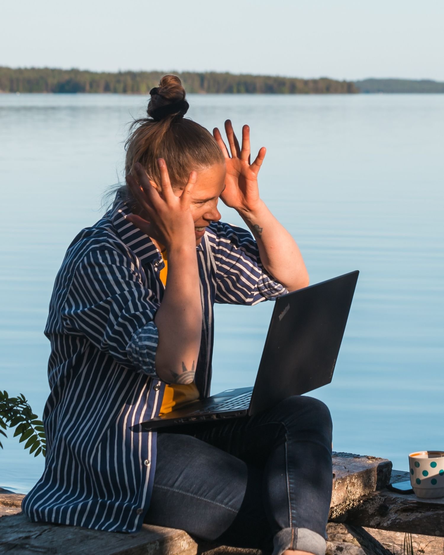 Henkilö, jolla on läppäri sylissään, pitää käsiään päänsä molemmin puolin jännittyneenä.
