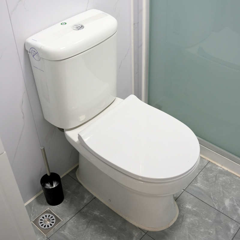 Clean white toilet in a bathroom with a toilet brush holder next to it.