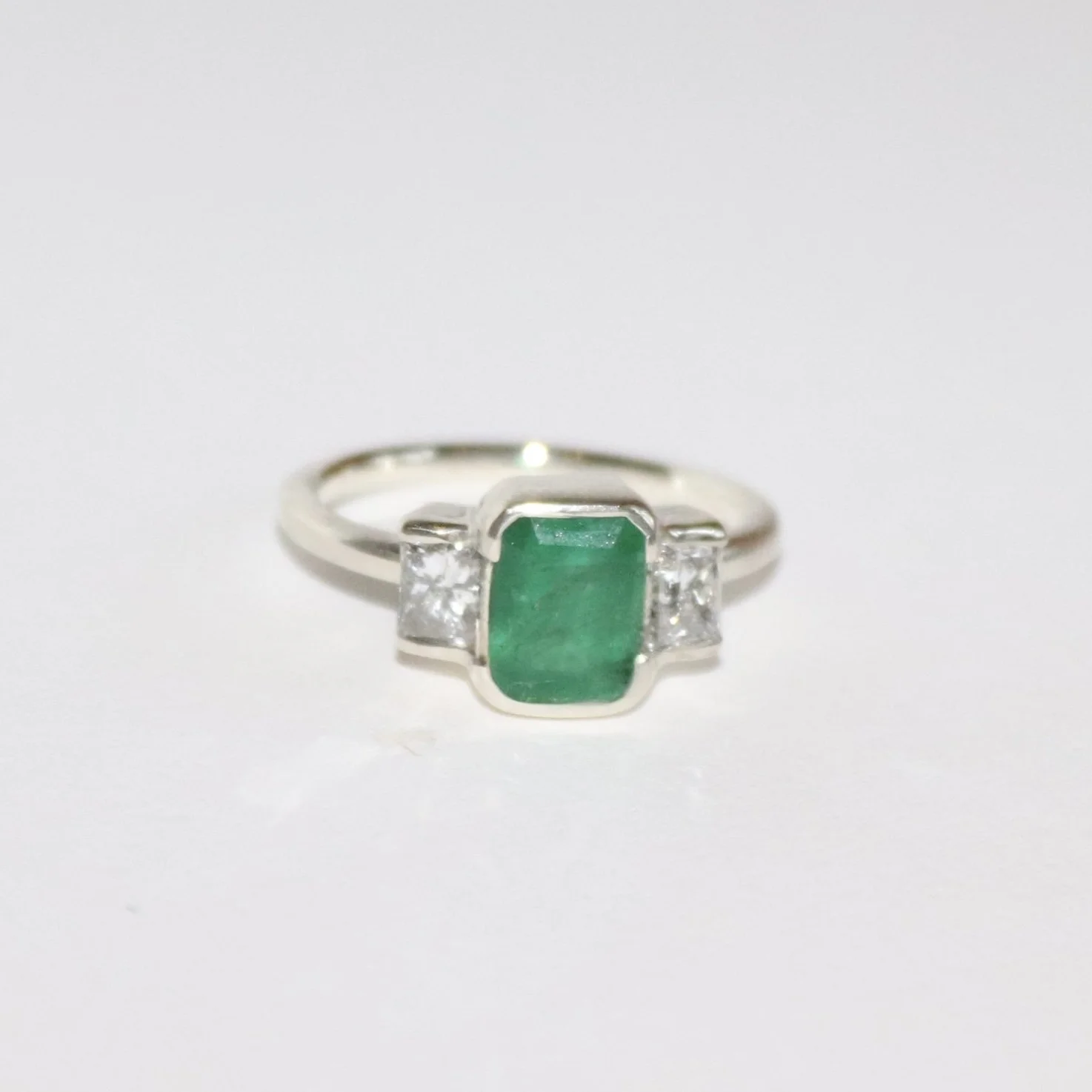 9ct white gold bezel set emerald and diamond engagement ring.