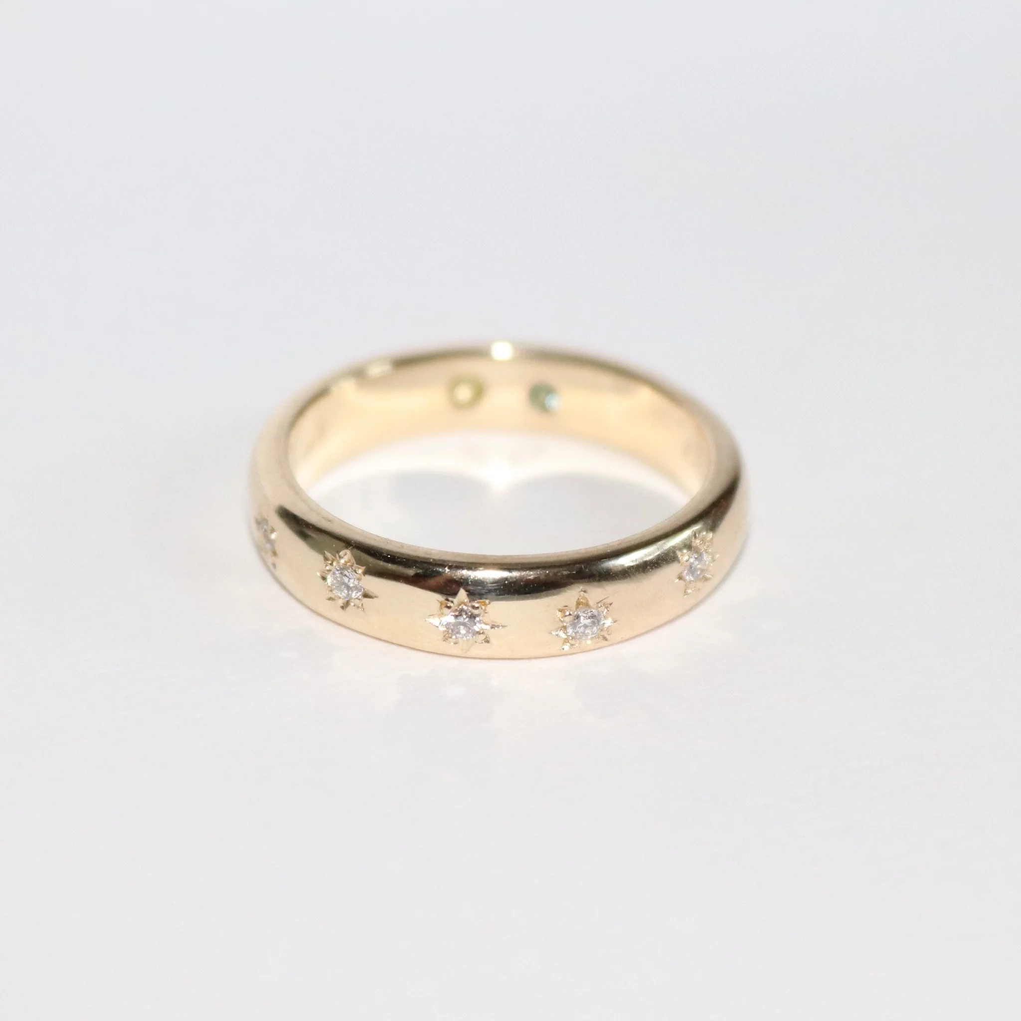 A bespoke 9ct yellow gold star set wedding band with hidden birthstones set inside the band.