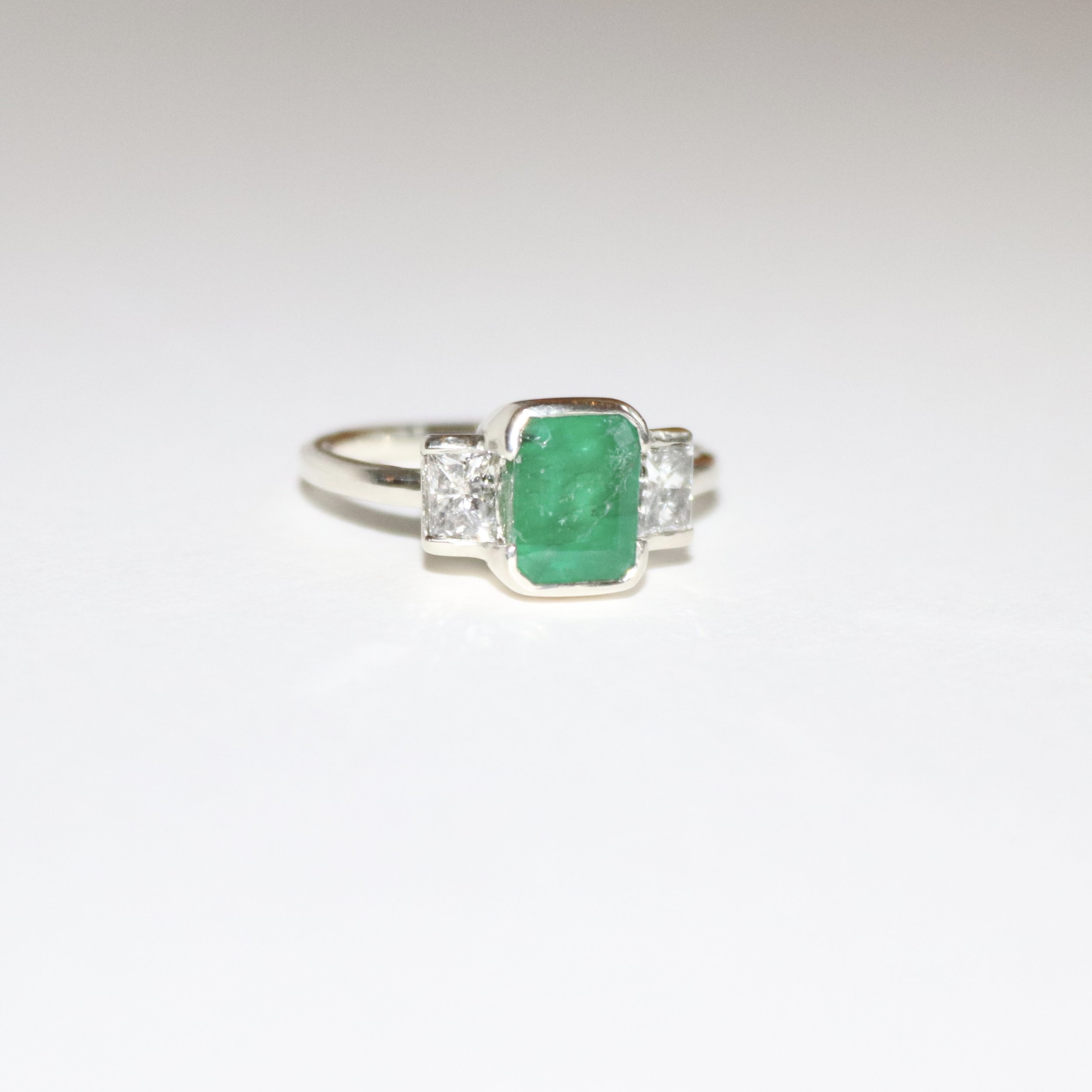 9ct white gold ring set with an emerald cut emerald bezel set with also two diamonds. 
