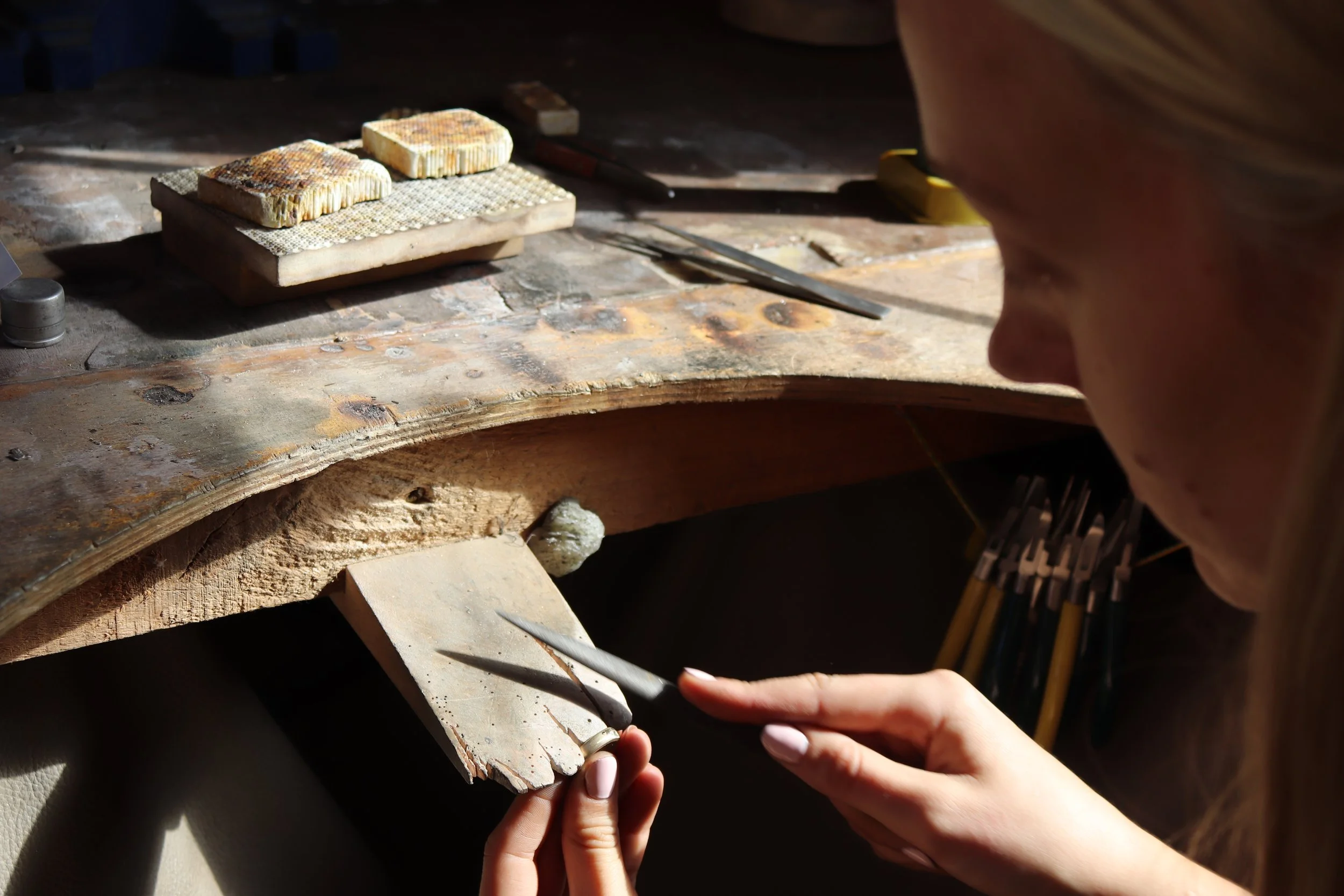 Close-up of a person working on a stone carving project at a workbench, with stone fragments and tools nearby.