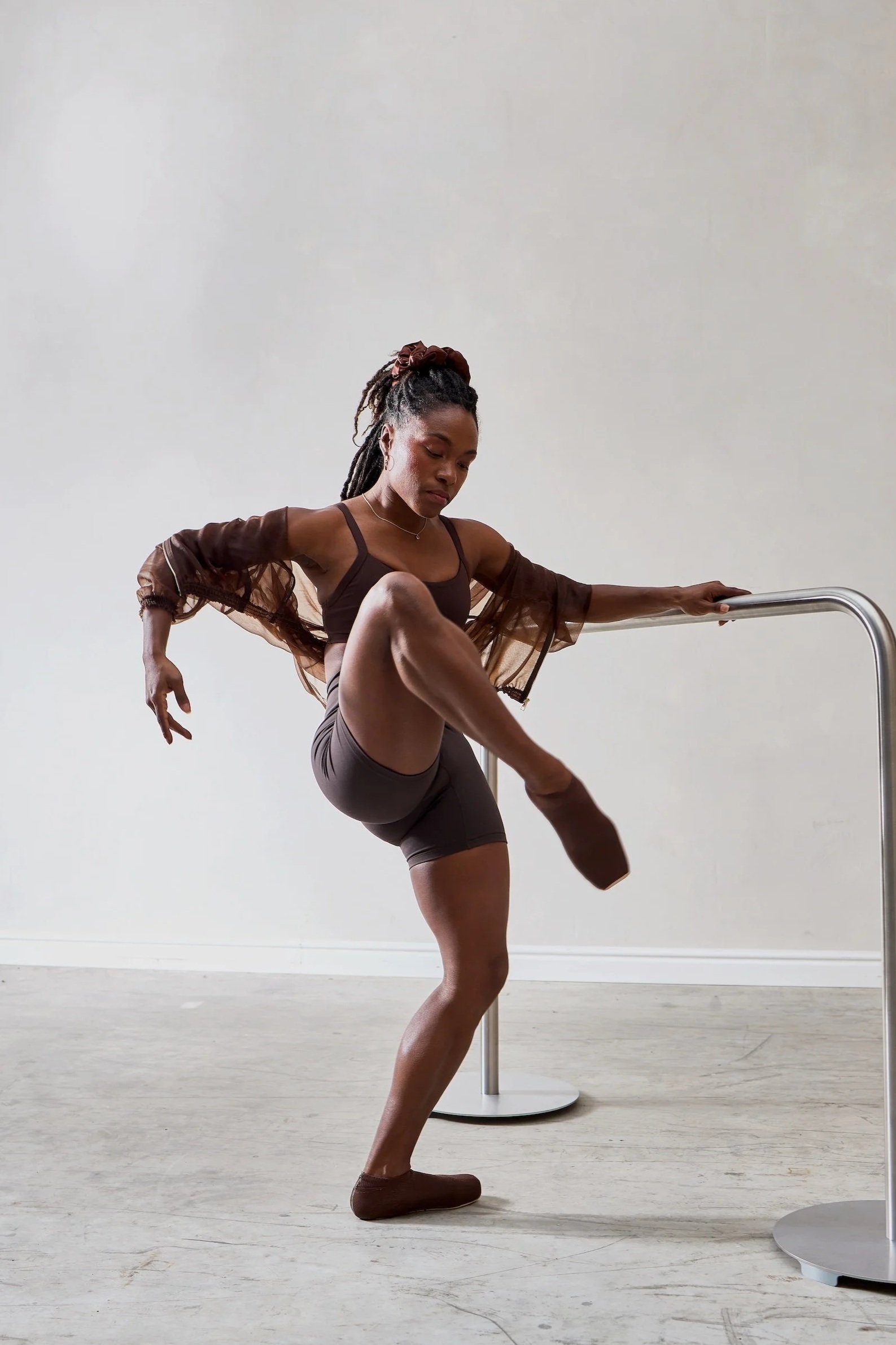 Athletische Bewegung einer BIPOC Frau an der Ballettstange.