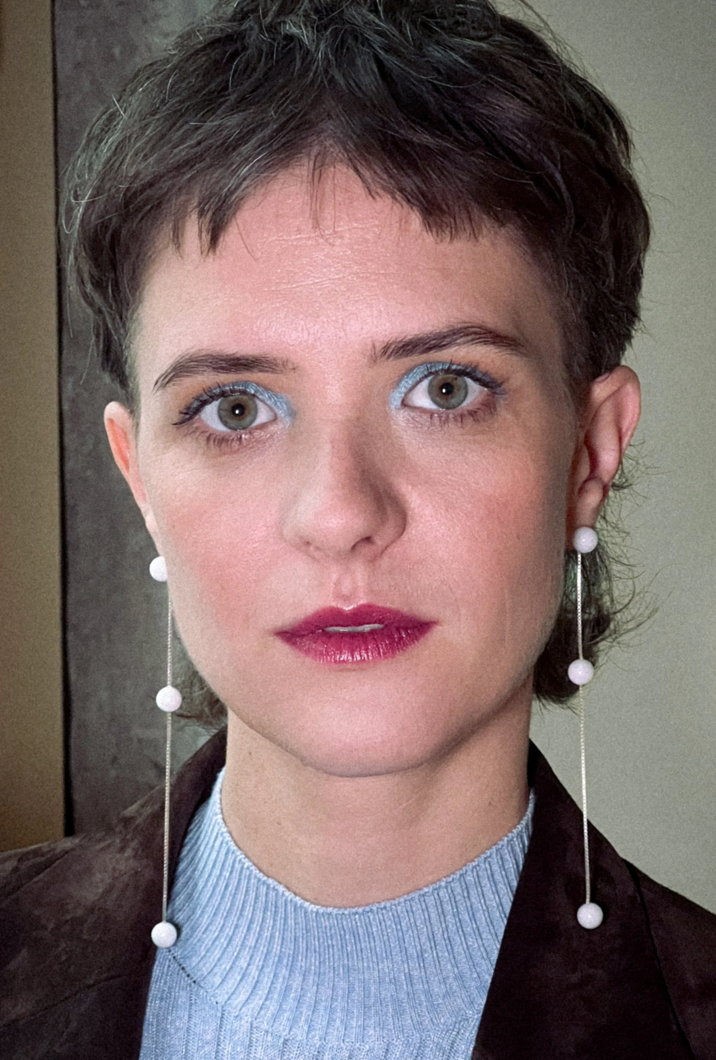 Liv Lisa Fries, Hauptdarstellerin der deutschen Serie Babylon Berlin, in einem kreativen Make-Up Look mit hellblauem Lidschatten, weinroten Lippen und einem strahlenden Teint.