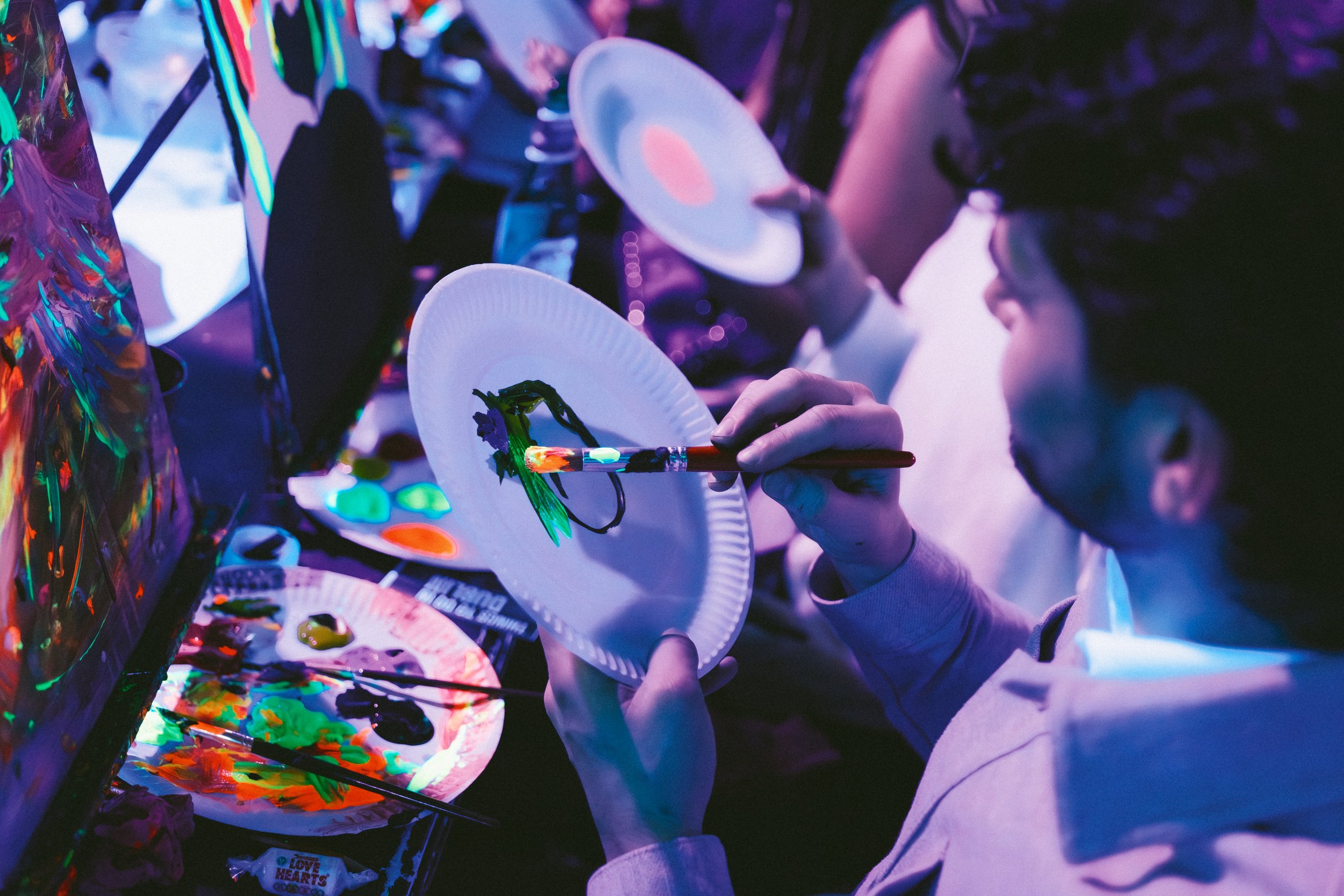 A happy girl laughing while she's painting a house with neon paints.