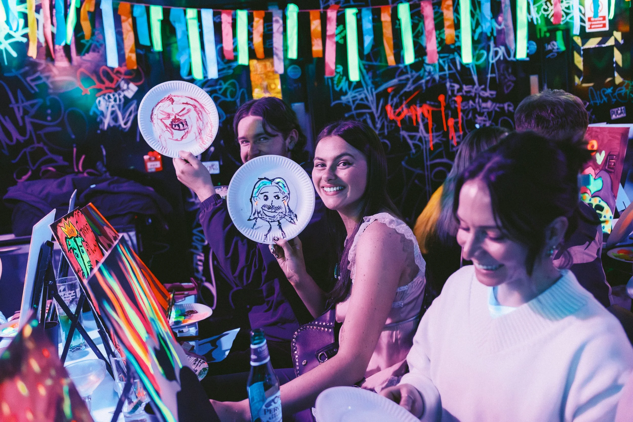 A young woman showing two bottles full of neon paint.