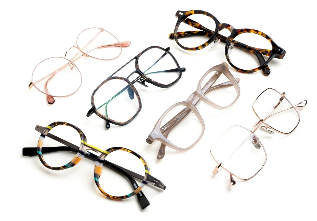 Collection of seven stylish eyeglasses and sunglasses with various frame styles and colors, placed on a white background.