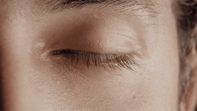 Close-up of a closed human eye with visible eyelashes and skin details.