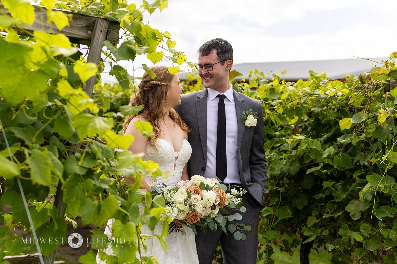 Four Daughters Vineyard & Winery wedding featuring a lush bridal bouquet in creamy whites, soft pinks, and unexpected brown blooms, with romantic wedding florals in Spring Valley, MN.
