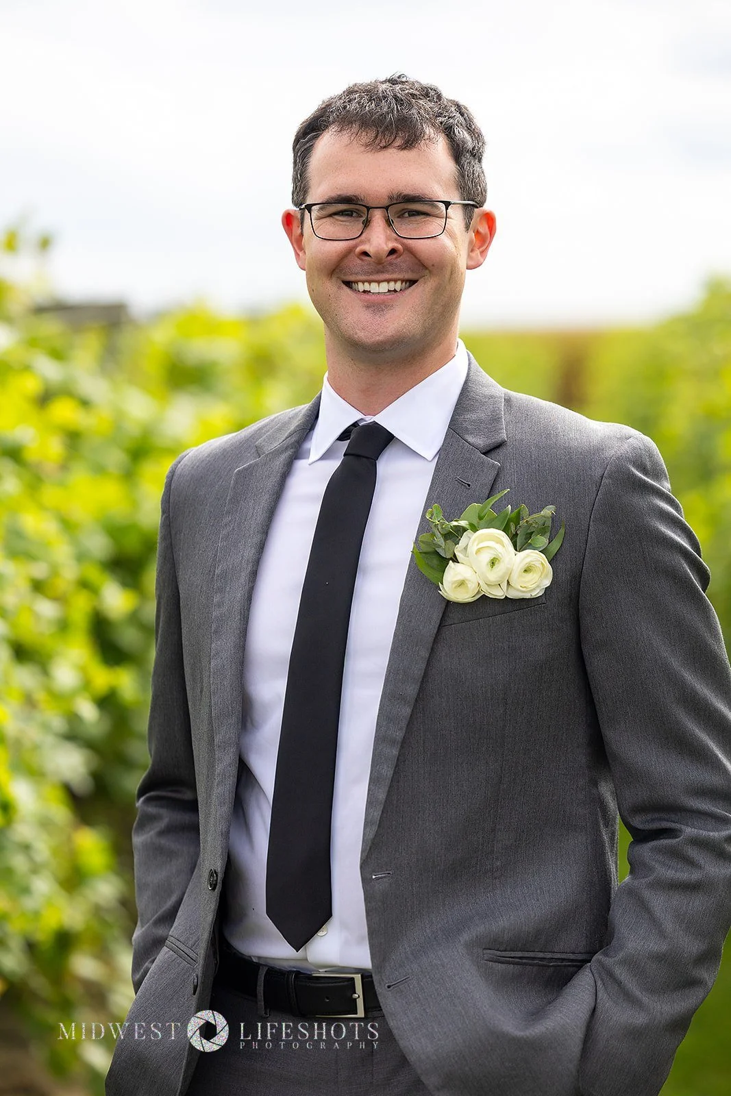 Four Daughters Vineyard & Winery wedding featuring a modern pocket boutonniere with ranunculus and romantic greenery in Spring Valley, MN.
