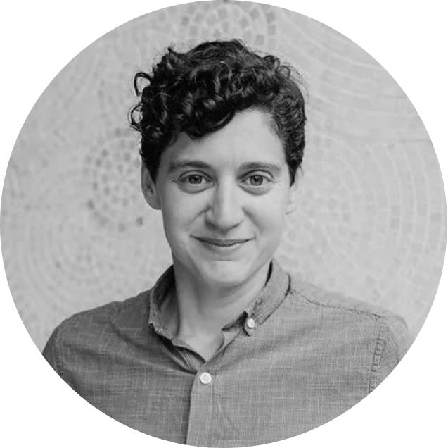 A black and white portrait of a young woman with short, curly hair, wearing a button-up shirt and smiling at the camera.