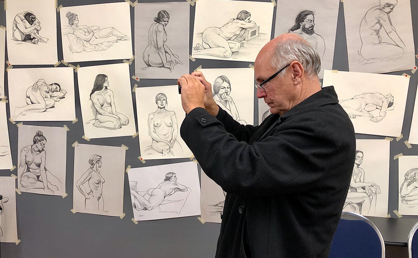 Featured Home Page Artist, May 5 – 11, 2026: John Tollett.
Caption: Artist Karl Whitaker snaps a photo of the gallery walls during John's 2020 life drawing exhibit.
For more information about John, select the image.