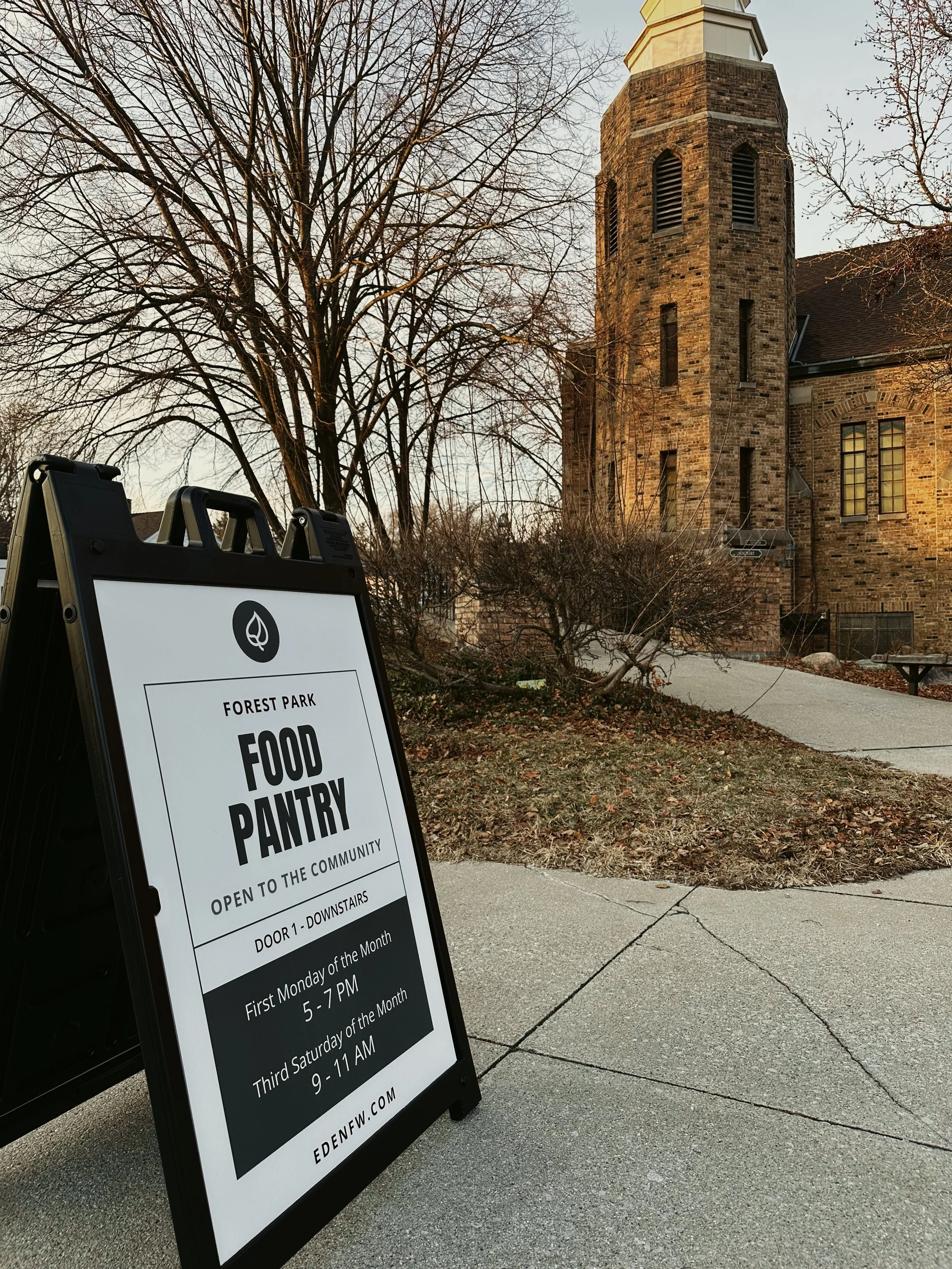 Informational sign for the Forest Park Food Pantry located on the sidewalk outside the building at 2100 Kentucky Ave, Fort Wayne, IN