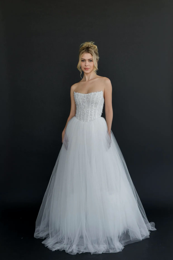 Gown "Nimbus" is crafted from intricately beaded embellished fabric, layered with soft organza and airy tulle. Featuring a flattering waistline and a structured, boned bodice, this gown beautifully blends a fairytale silhouette with contemporary eleg