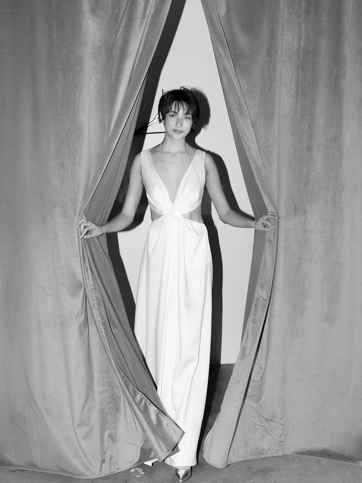 Crafted from soft ivory crepe, this gown is the perfect balance of comfort and glamour. Designed for the more daring bride, its striking cutouts and plunging neckline make a bold statement while remaining effortlessly elegant and timeless.