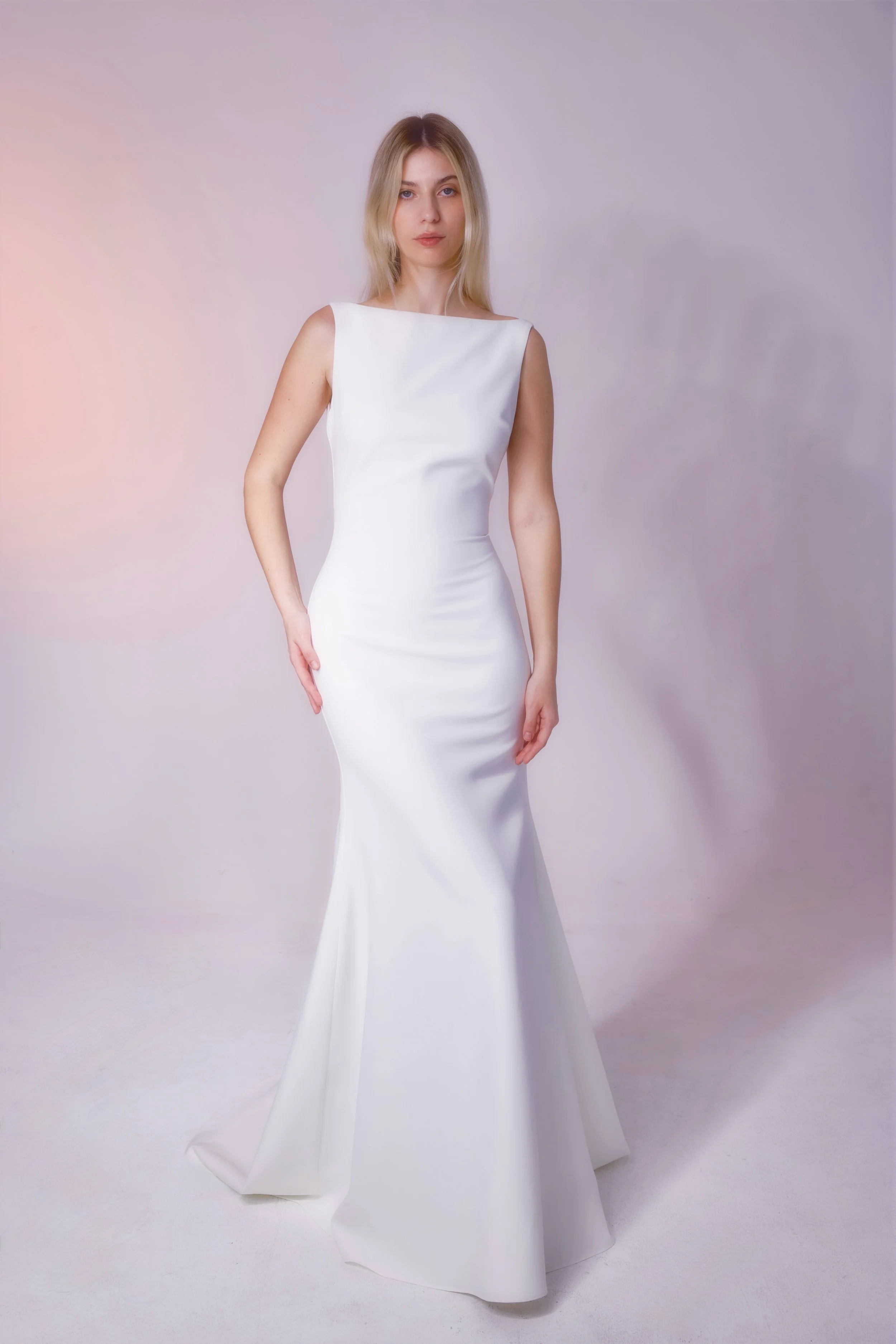 Crafted from luxurious crepe fabric, this gown features a stunning high neckline, elegant low back, and beautifully fitted silhouette for a sleek, sophisticated look.