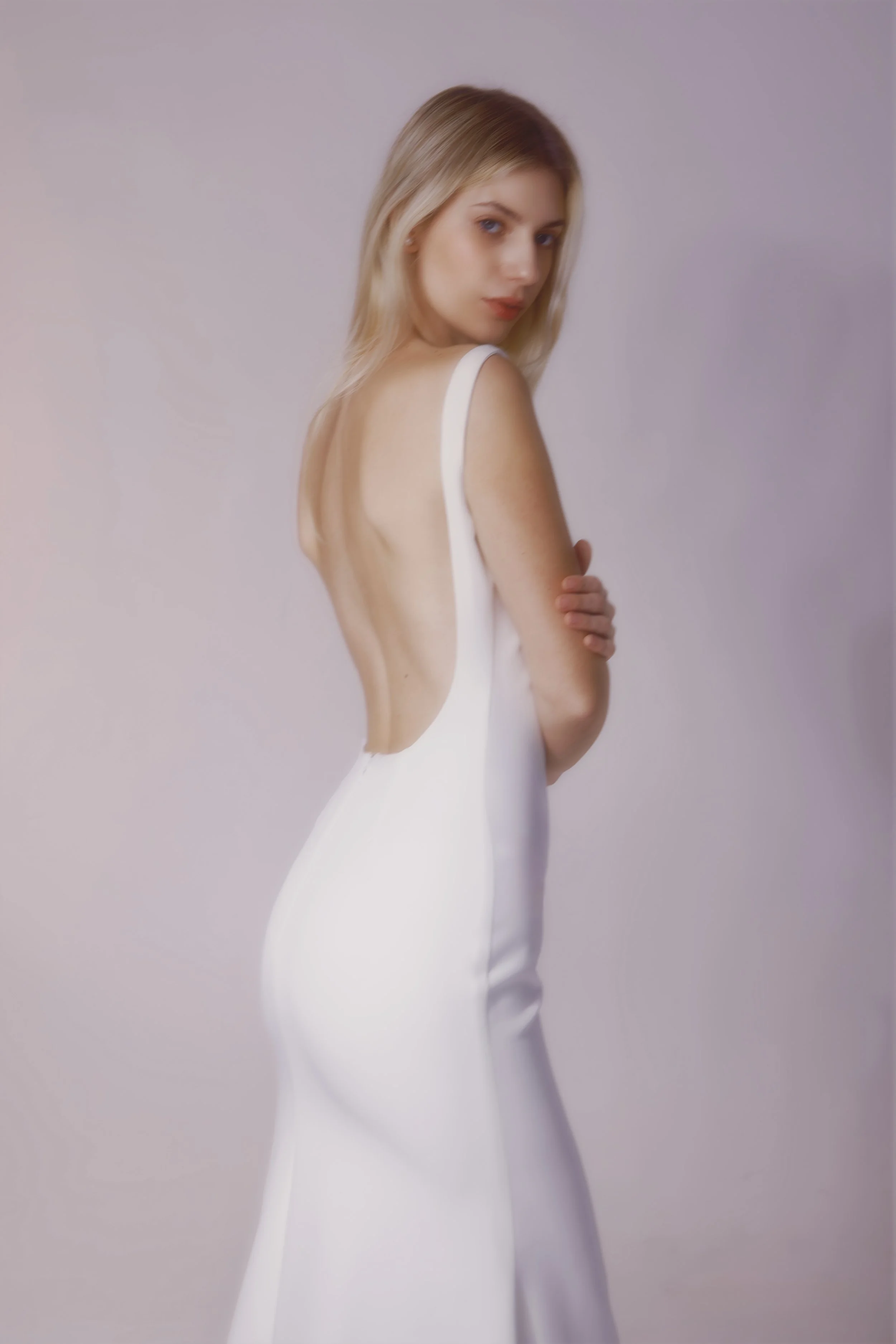 Crafted from luxurious crepe fabric, this gown features a stunning high neckline, elegant low back, and beautifully fitted silhouette for a sleek, sophisticated look.