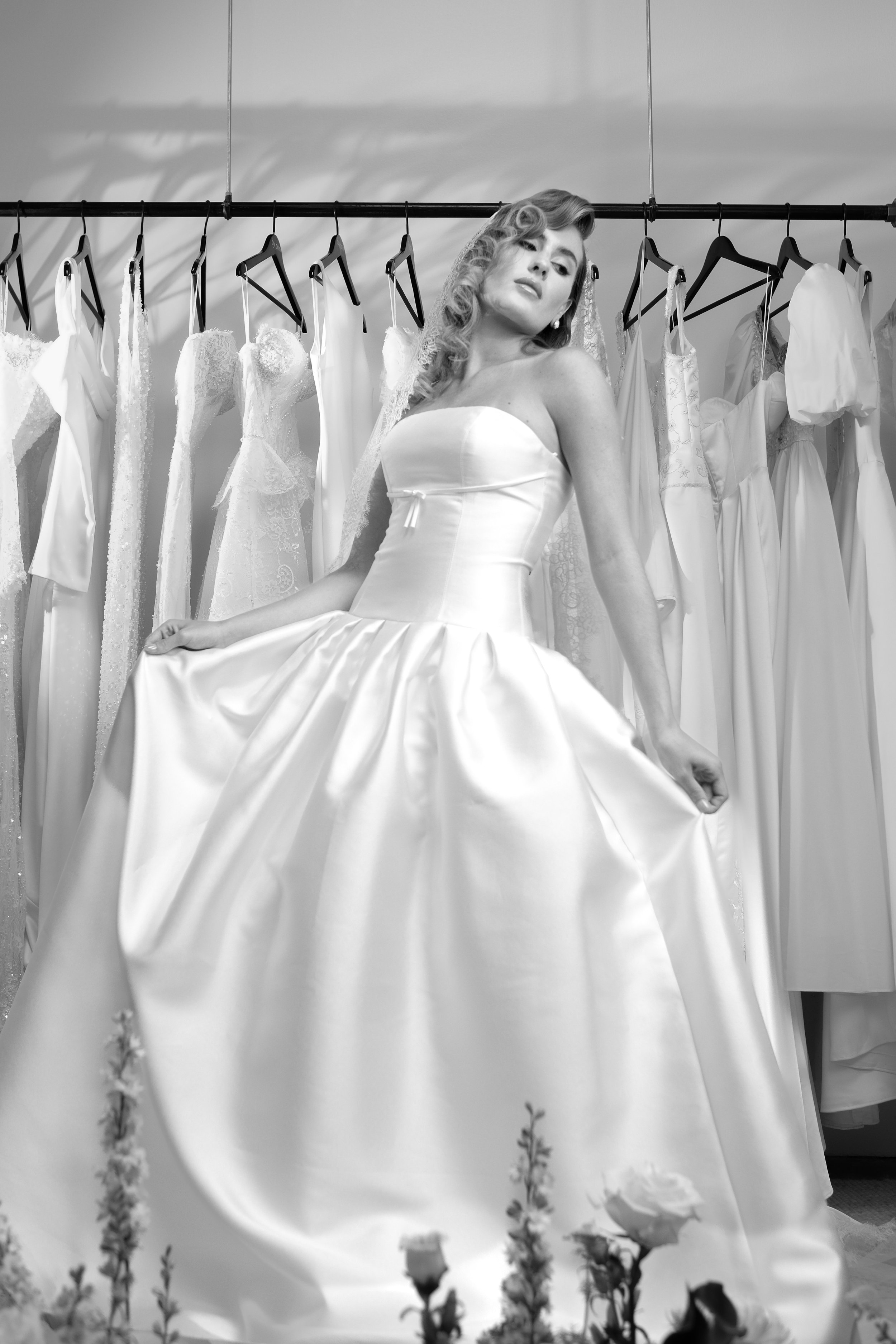 The 'Monroe' gown features elegant pleating at the hips, a flattering drop-waist silhouette, and a delicate bow just below the bust. Feminine and sophisticated, this gown exudes a timeless yet effortlessly chic charm.