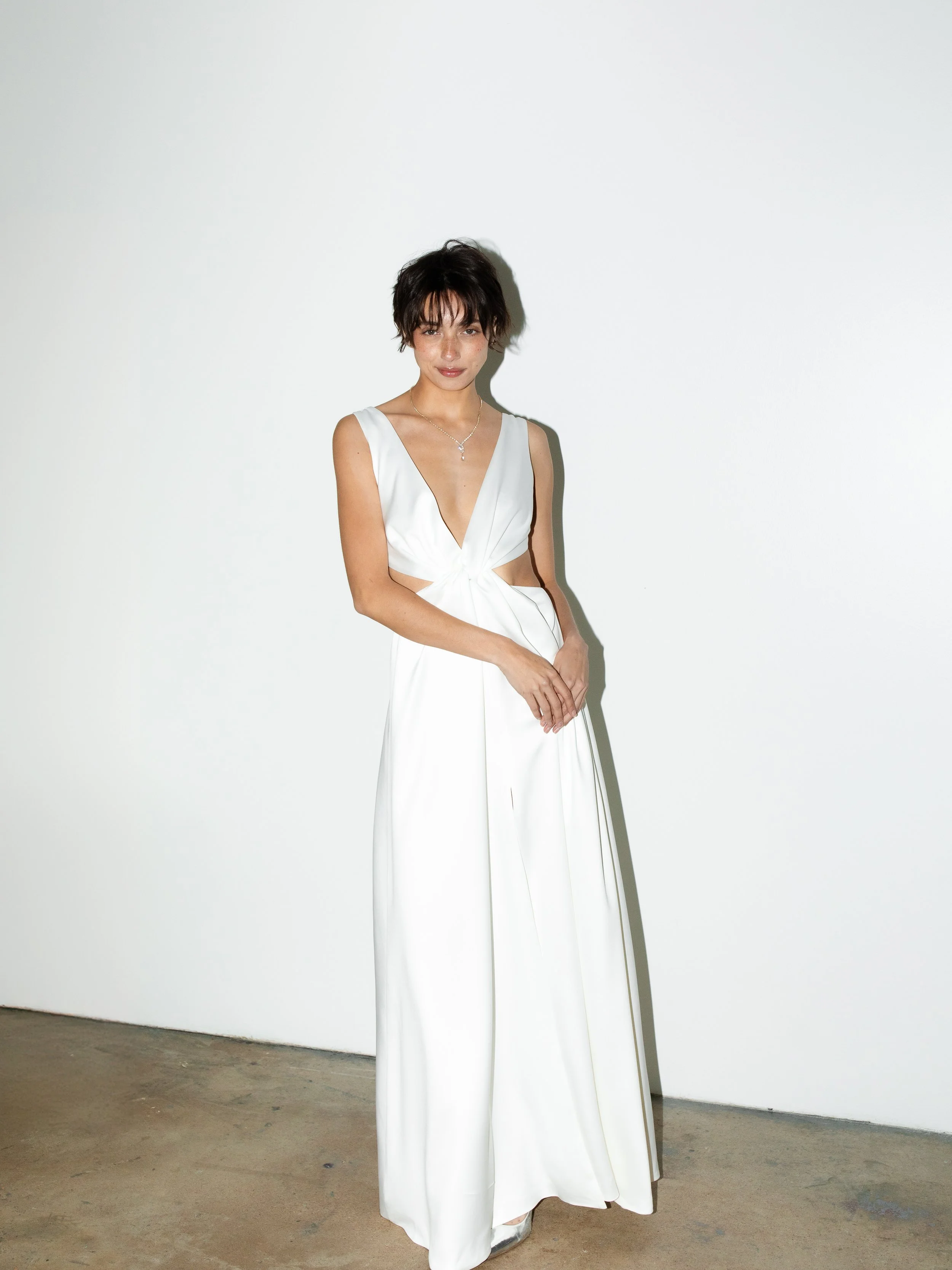 Crafted from soft ivory crepe, this gown is the perfect balance of comfort and glamour. Designed for the more daring bride, its striking cutouts and plunging neckline make a bold statement while remaining effortlessly elegant and timeless.