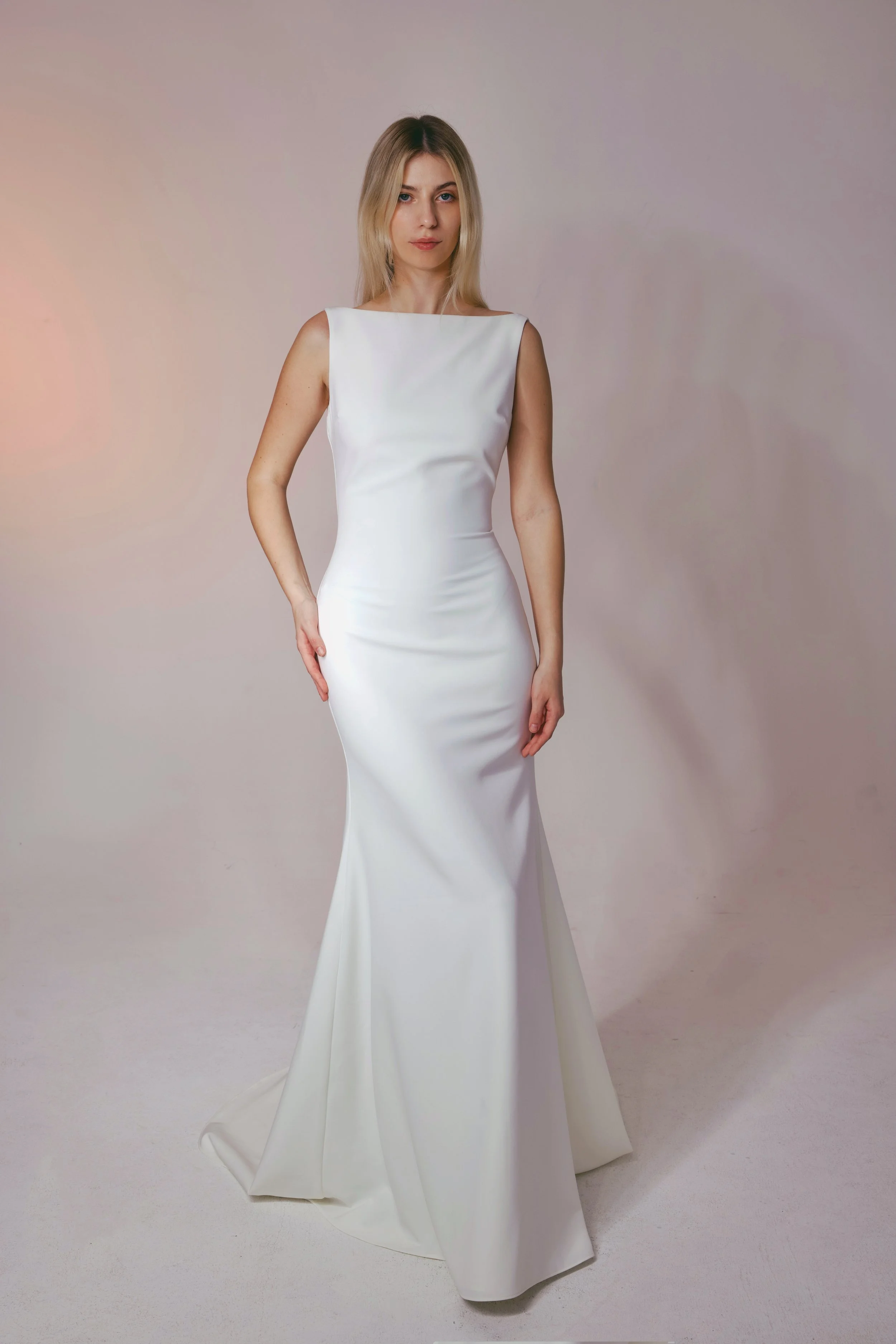 Crafted from luxurious crepe fabric, this gown features a stunning high neckline, elegant low back, and beautifully fitted silhouette for a sleek, sophisticated look.