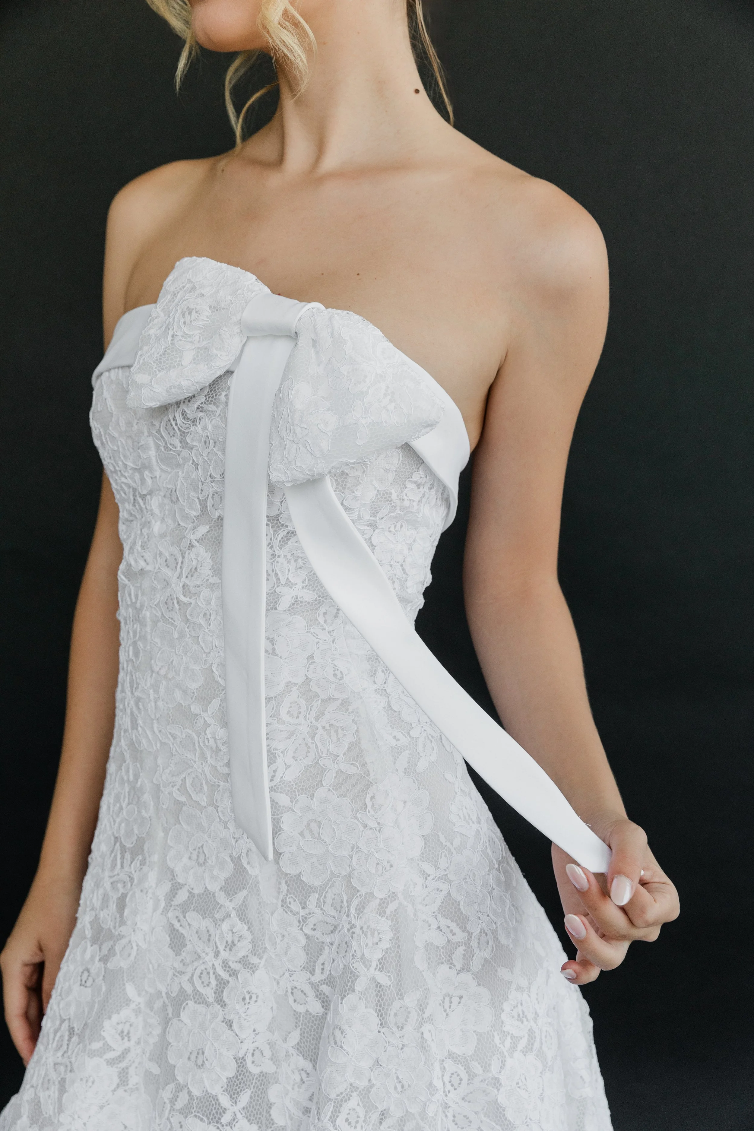 Gown "Daffodil" is crafted from stunning corded floral lace, delicate organza, and soft satin bridal lining. Featuring a detachable bow detail, its fitted bodice gently transitions into a flowing skirt, creating a look that is both sweet and distinct