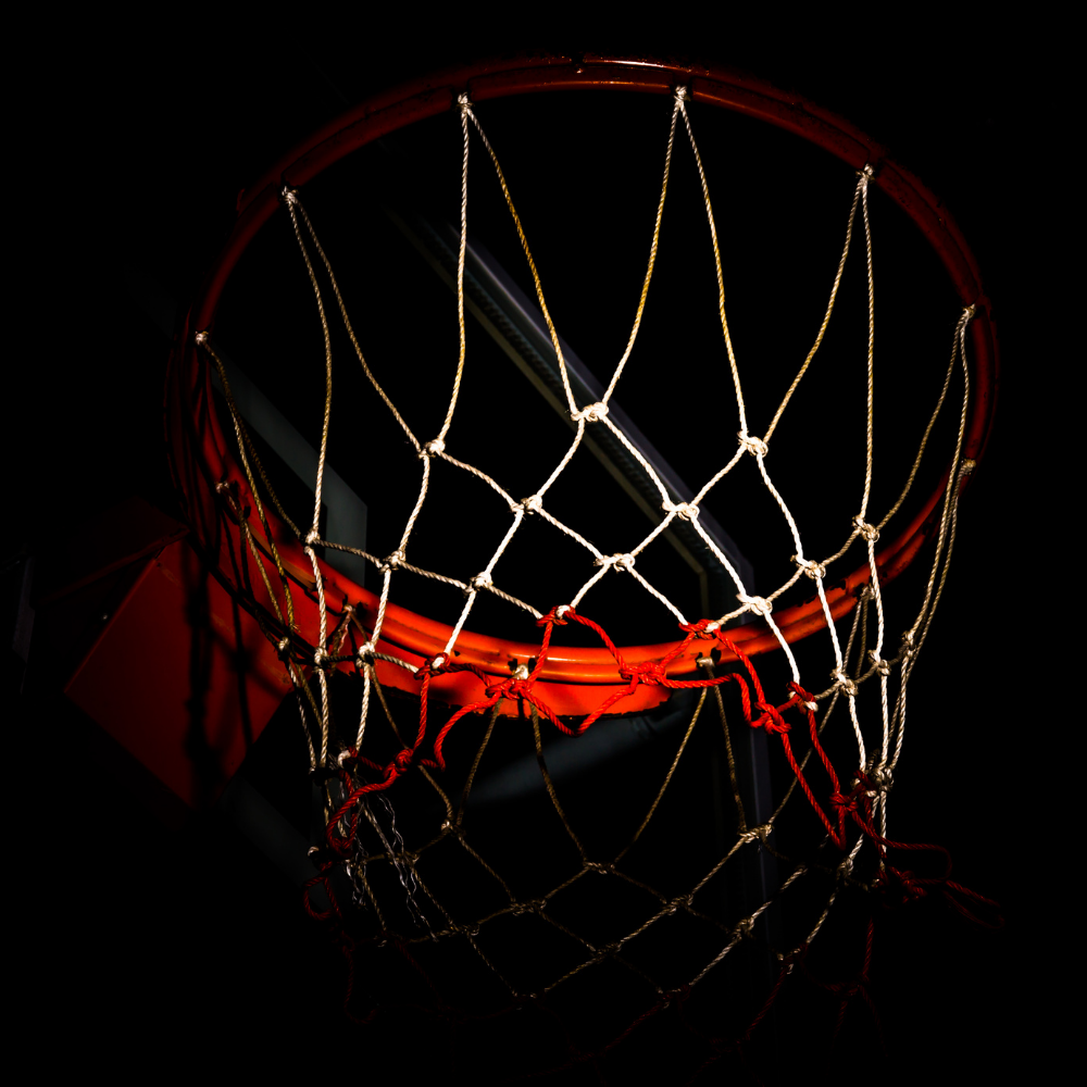 A basketball hoop with a neon red rim and white net against a black background.