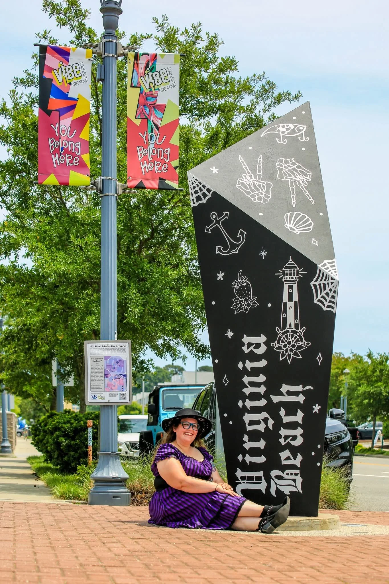 Virginia Beach Street Art Festival mural by Rebecca Coelho featuring gothic "Virginia Beach" lettering, local landmarks, and the upper section of the four-sided sculpture decorated with coastal-inspired imagery.