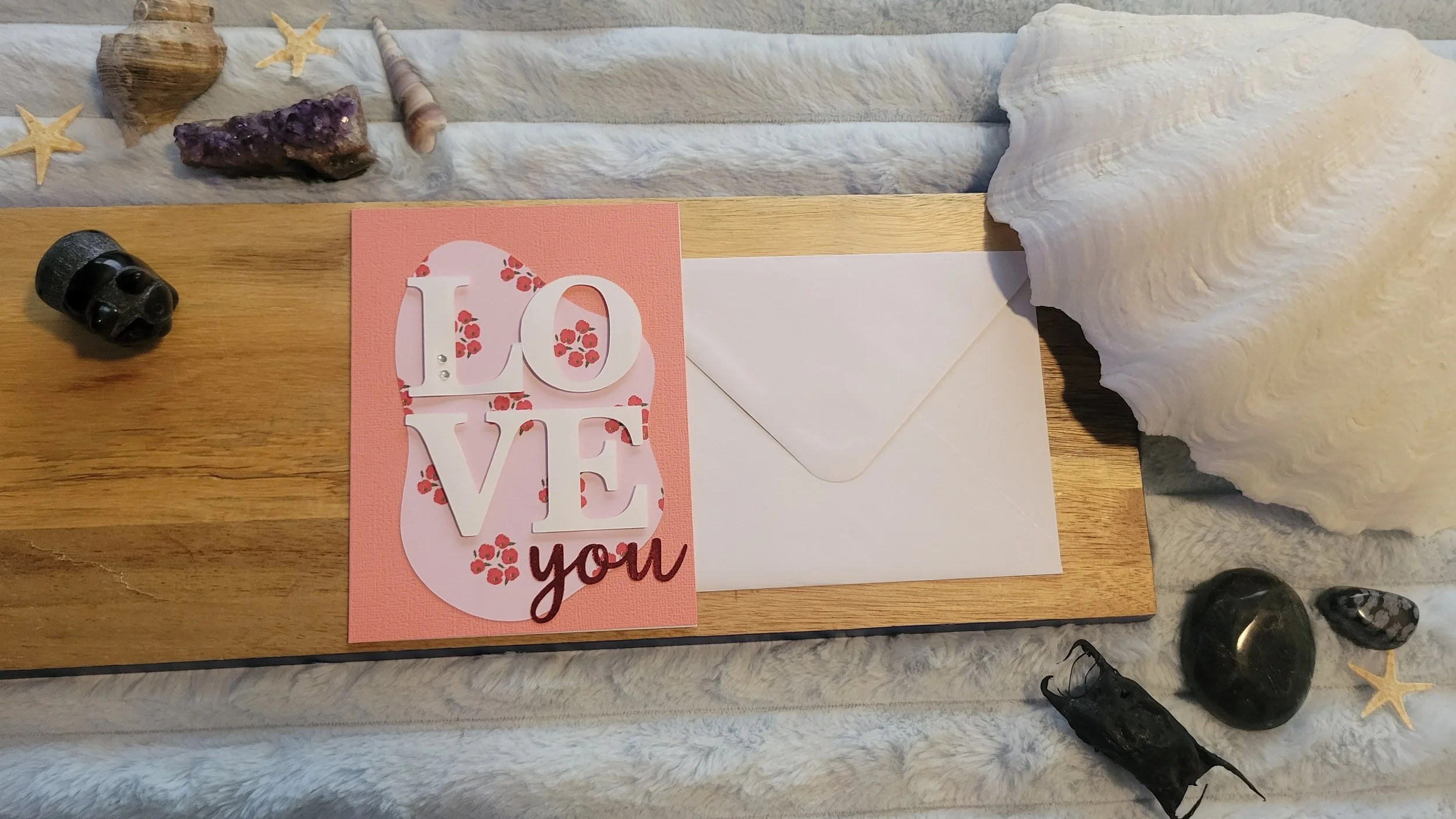 Pink handmade card with a pale pink and red poppy-patterned abstract shape, layered white “LOVE” lettering, and shiny red script “you” at the bottom.