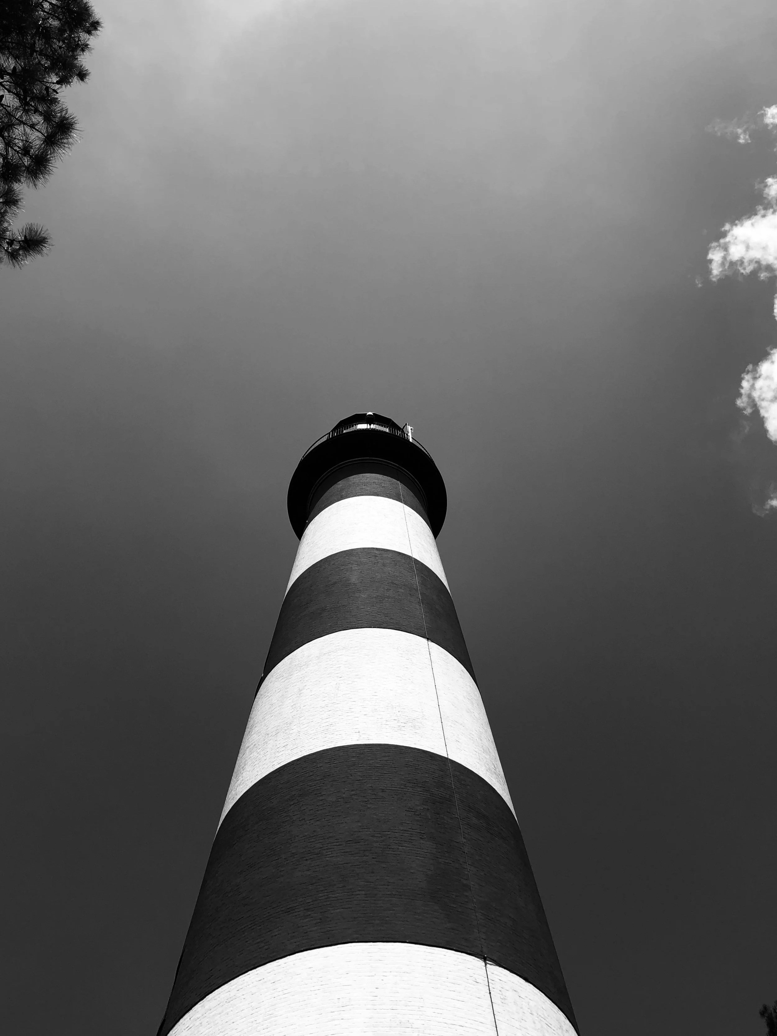Greyscale Photo of black and white striped lighthouse located on Chincoteague Island, VA by Anthony Stacy on Unsplash