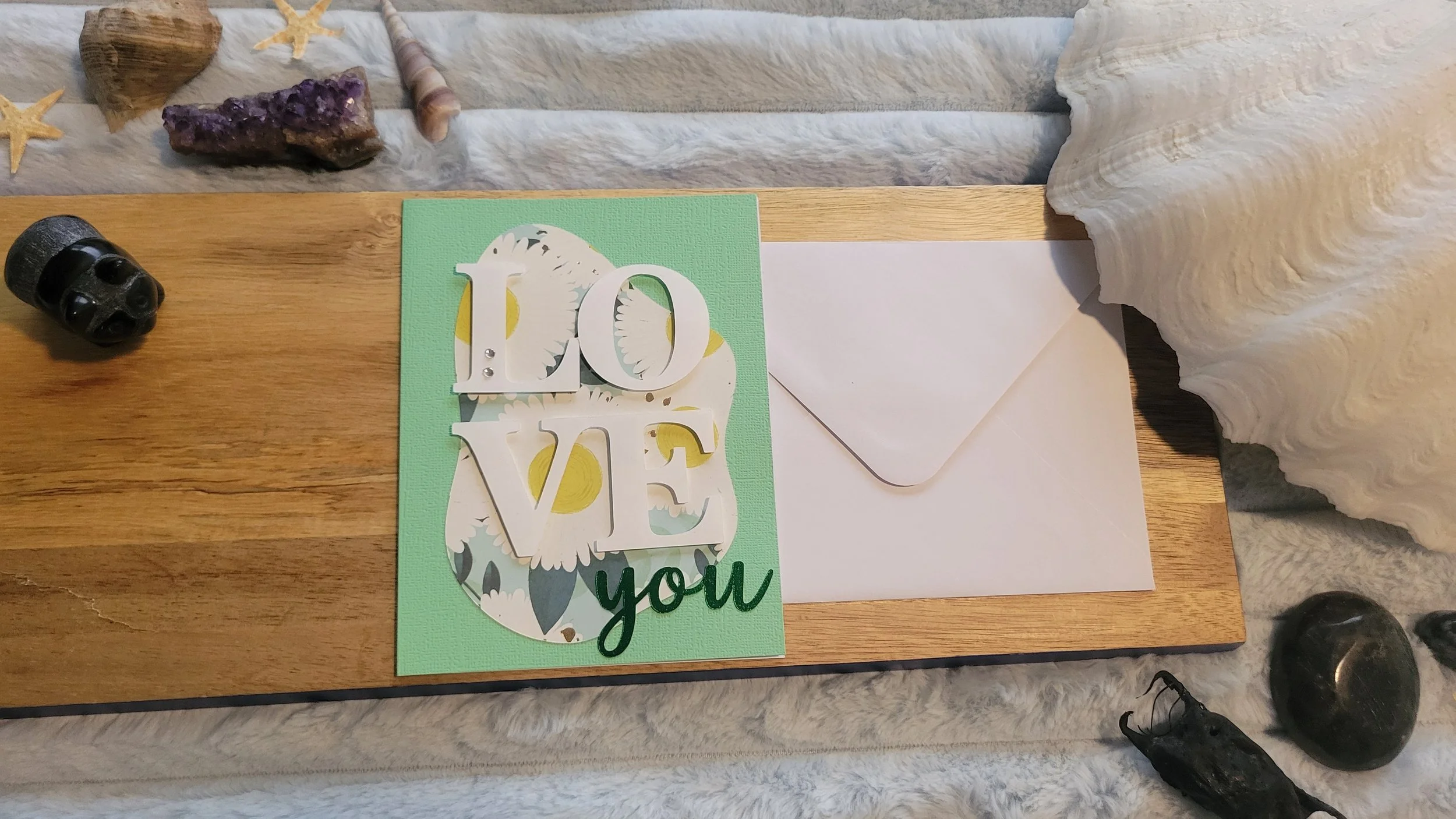 Light Green handmade card with a sunflower-patterned abstract shape, layered white “LOVE” lettering, and shiny green script “you” at the bottom