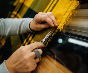hands cutting yellow fabric with scissors, symbolizing rebuilding routines and intentional living systems