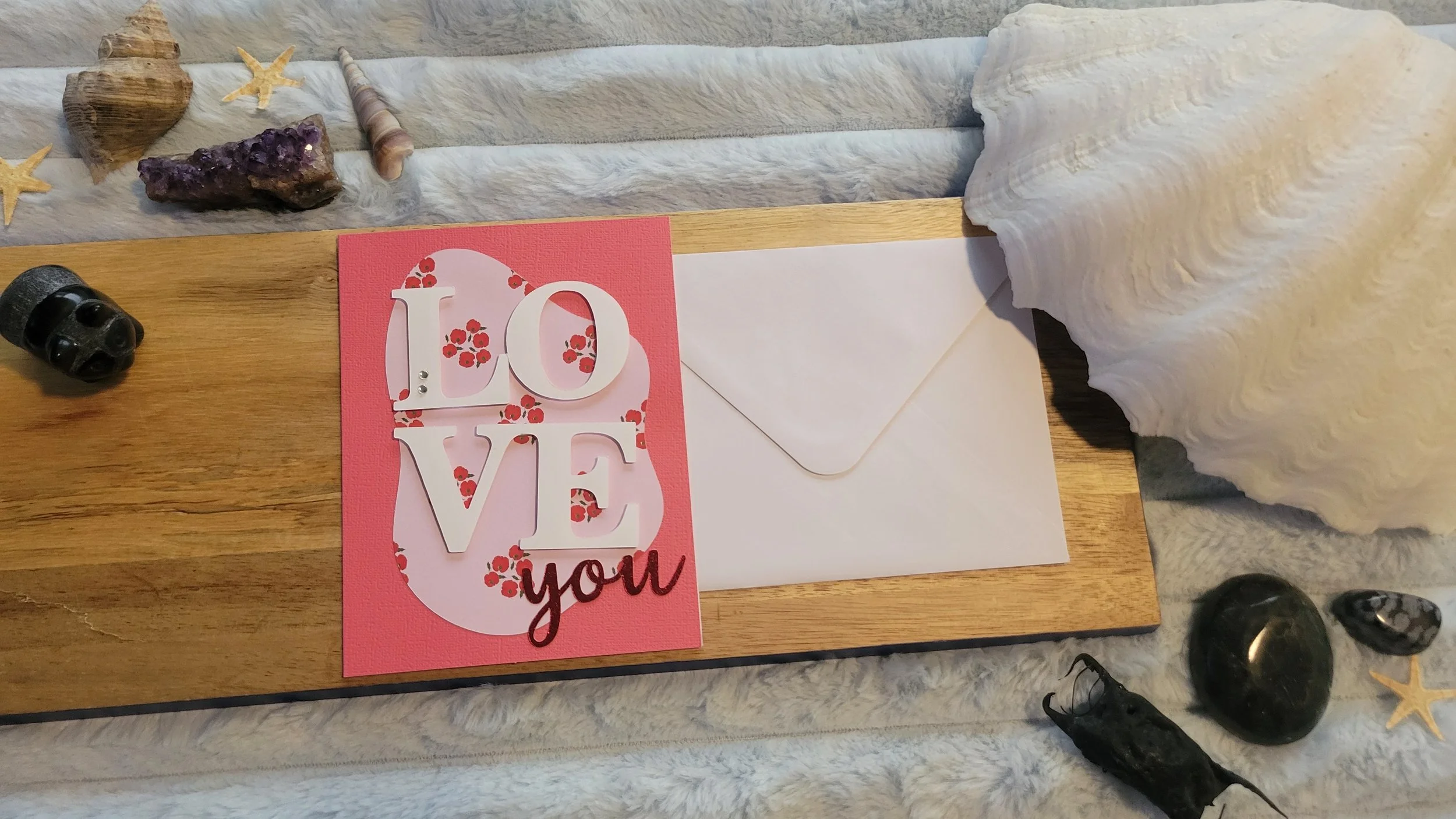 Pink handmade card with a pale pink and red poppy-patterned abstract shape, layered white “LOVE” lettering, and shiny red script “you” at the bottom.