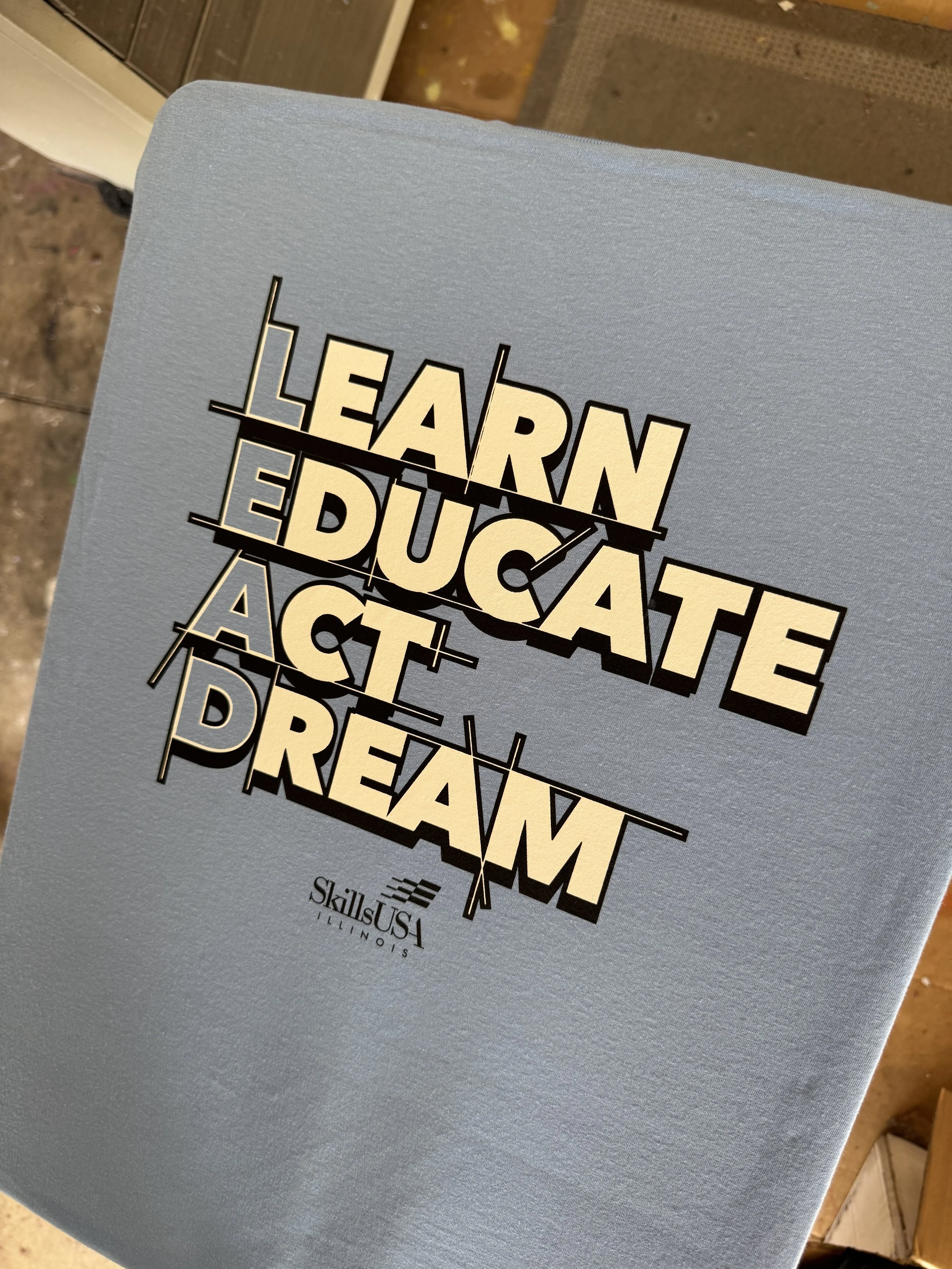 Close-up of a book cover with the title 'Learn, Educate, Act, Dream' in bold typography, with a light blue background.